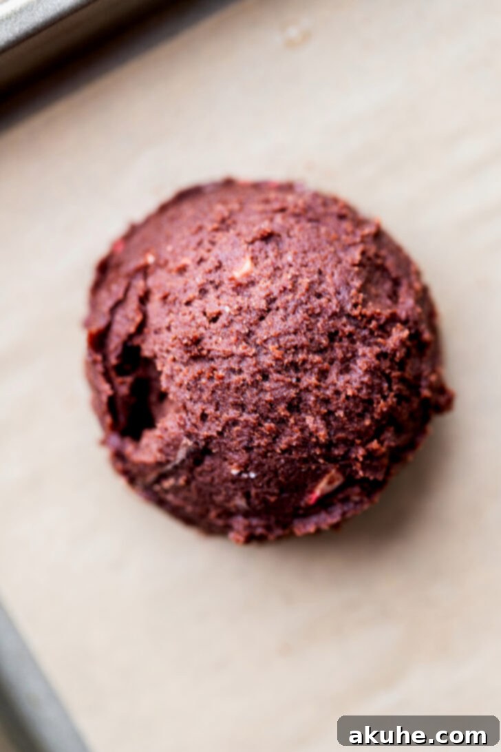 Scooped cookie dough ball on parchment paper, ready for chilling.