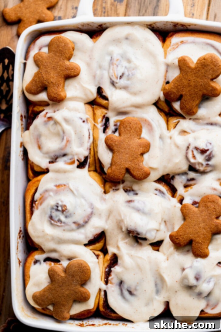 Spiced Gingerbread Swirl Buns 3 Close up view of the golden-brown tops of gingerbread cinnamon rolls with melting icing.