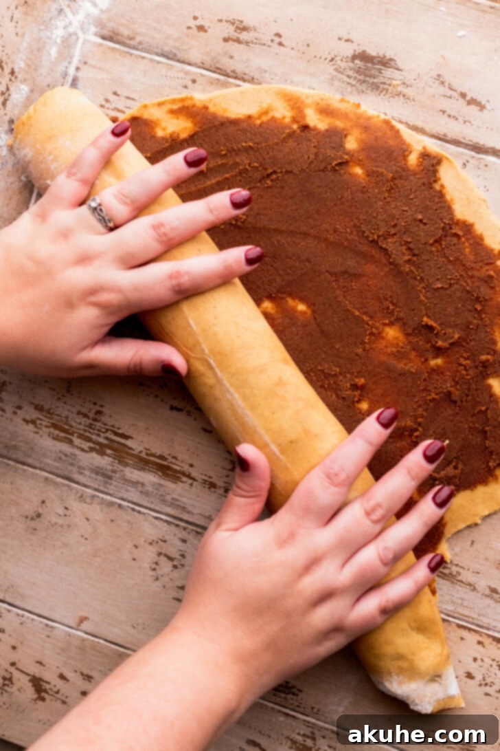 Spiced Gingerbread Swirl Buns 6 The dough is carefully rolled into a tight log after the filling has been applied, showcasing the swirling layers.