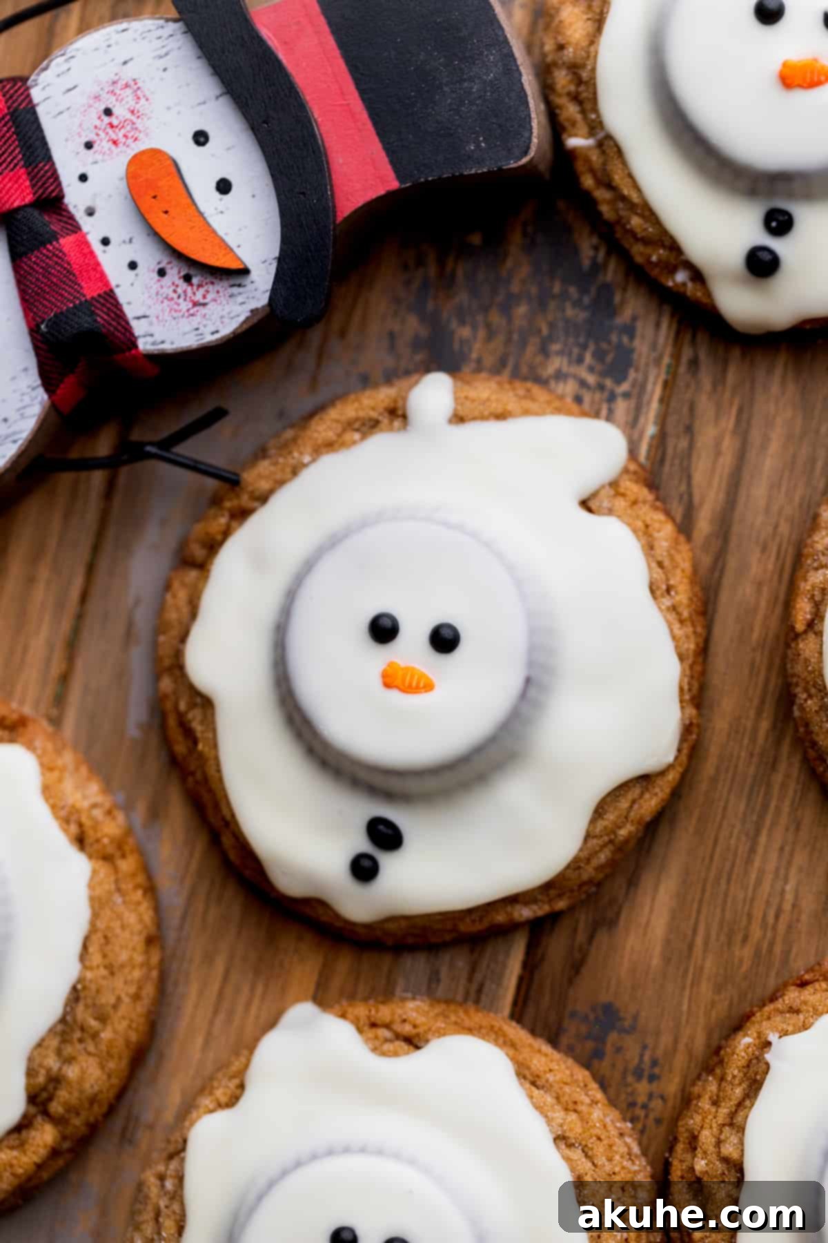 Close up of snowman cookies, showing the melted white chocolate and festive sprinkles on a gingerbread base.