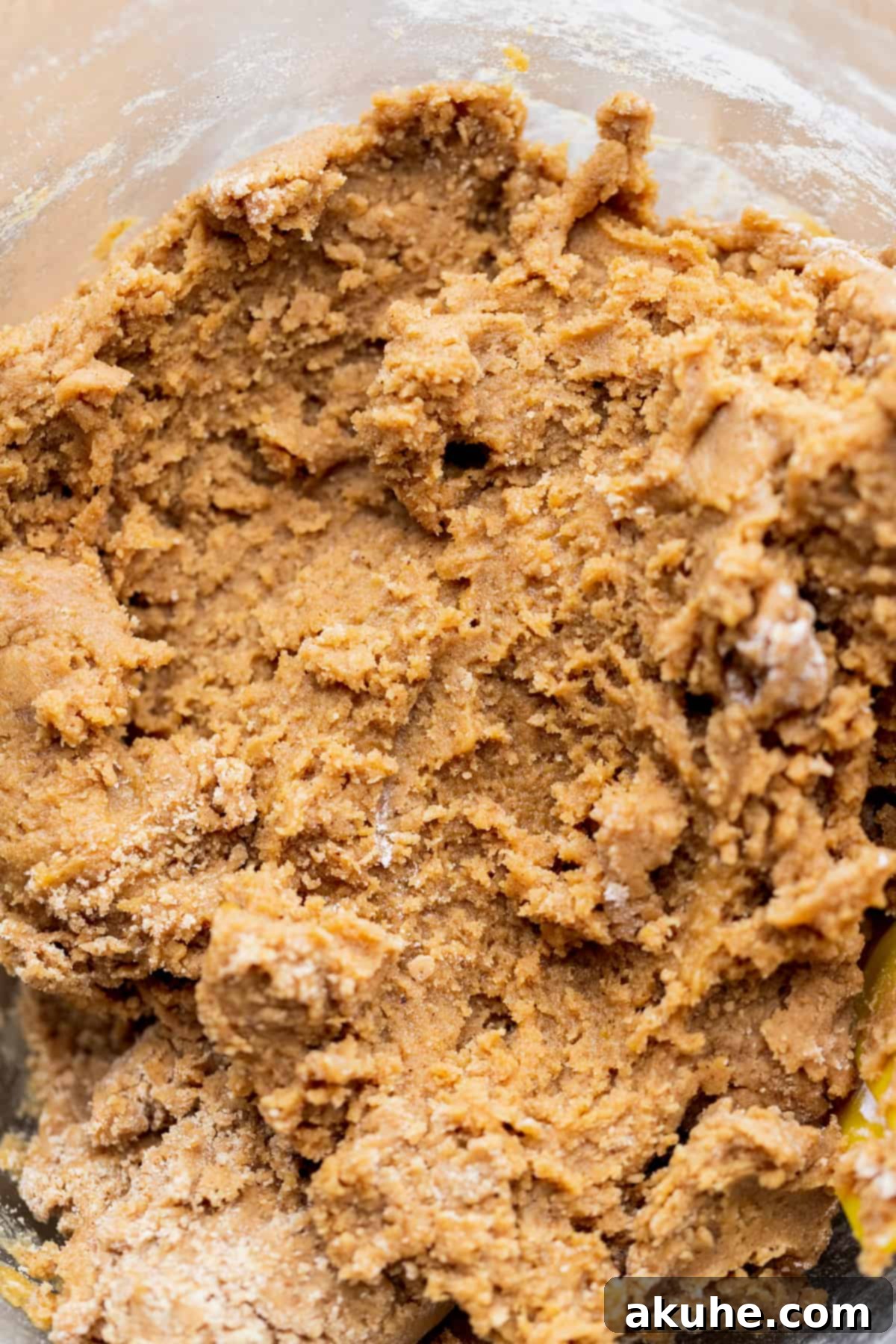 Finished gingerbread cookie dough in a clear glass bowl, showcasing its rich brown color.