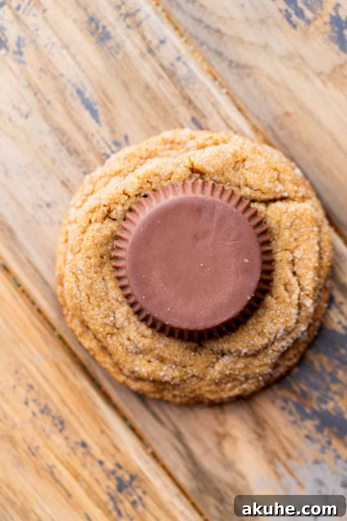 One gingerbread cookie topped with an upside-down peanut butter cup, ready for white chocolate.