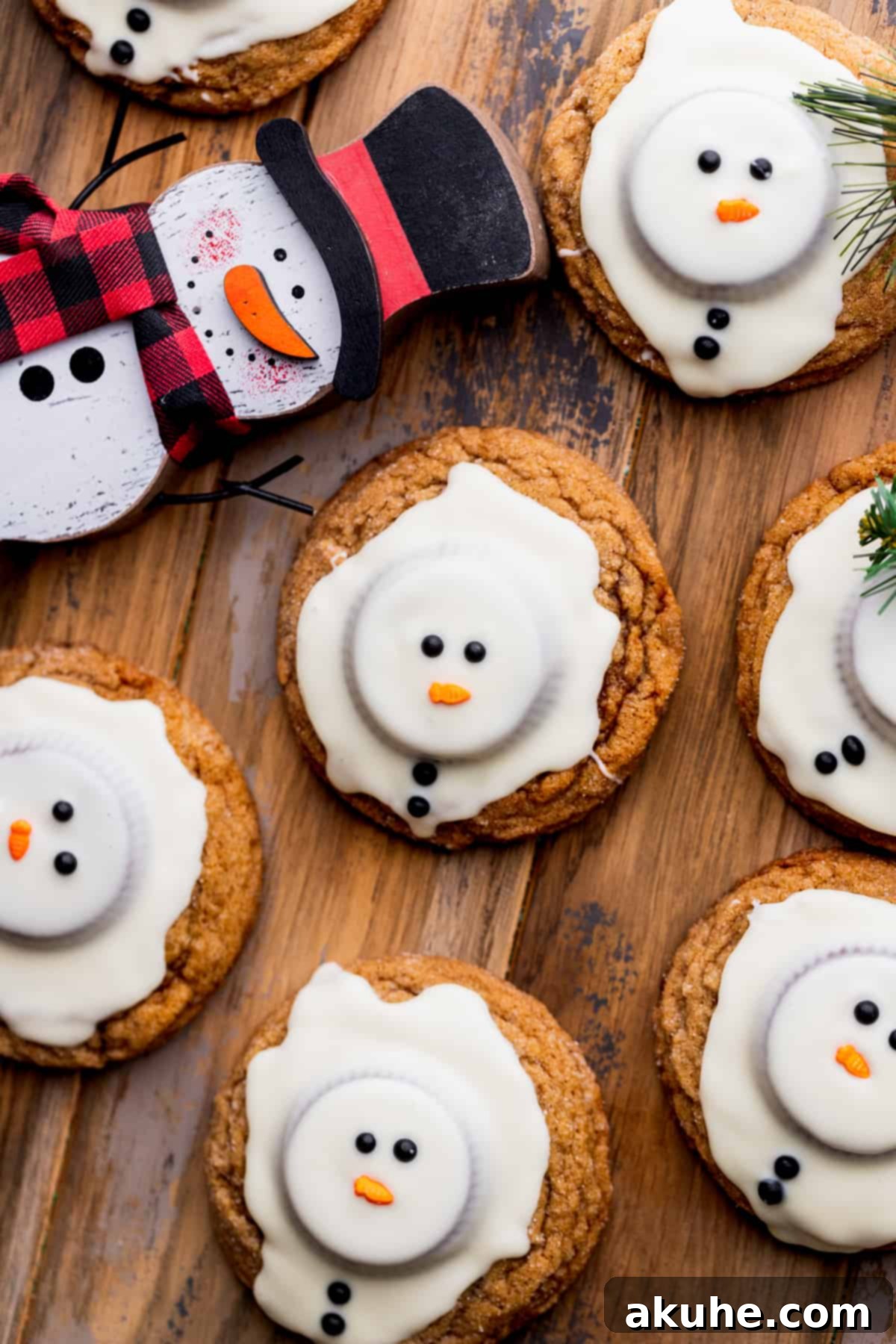 A batch of decorated snowman cookies, each with its unique sprinkle face, arranged on a cooling rack.