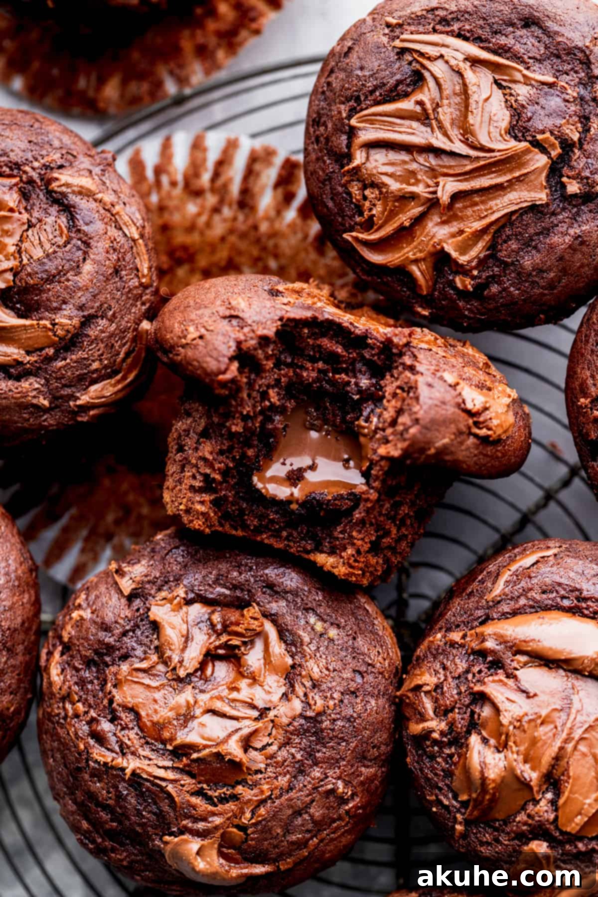 A perfectly baked Nutella muffin with a bite taken out, showcasing its rich chocolate crumb and gooey hazelnut center, resting on a cooling wire rack.