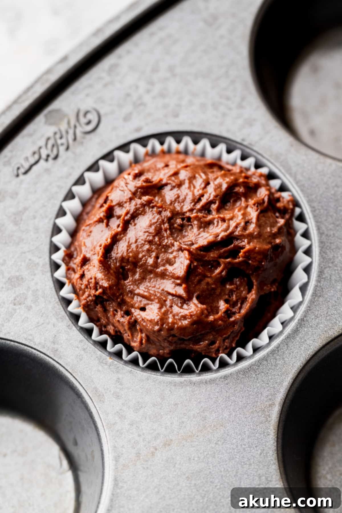 Muffin batter filled into a muffin pan, showing the technique of filling alternating cups for optimal rise.