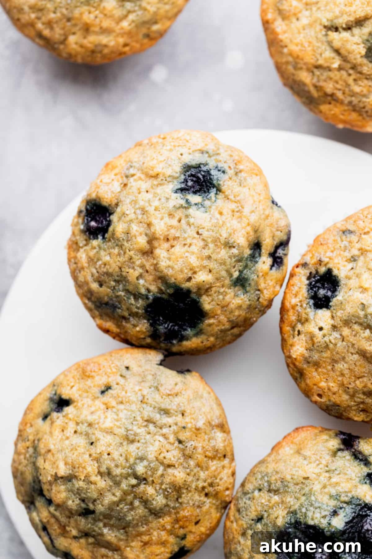 Irresistible Banana Blueberry Muffins 3 Top view of golden-brown banana blueberry muffins cooling on a rack, sprinkled with coarse sugar.