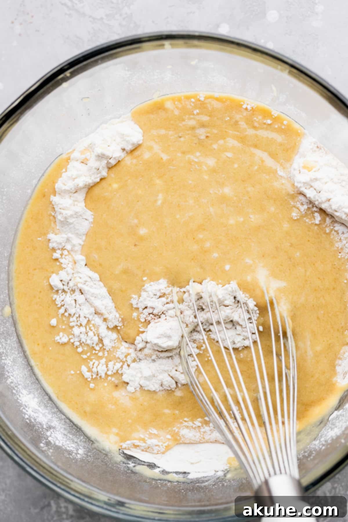 Irresistible Banana Blueberry Muffins 4 Close-up of wet ingredients (mashed bananas, butter, sugar, eggs, sour cream, vanilla) combined in a glass bowl.