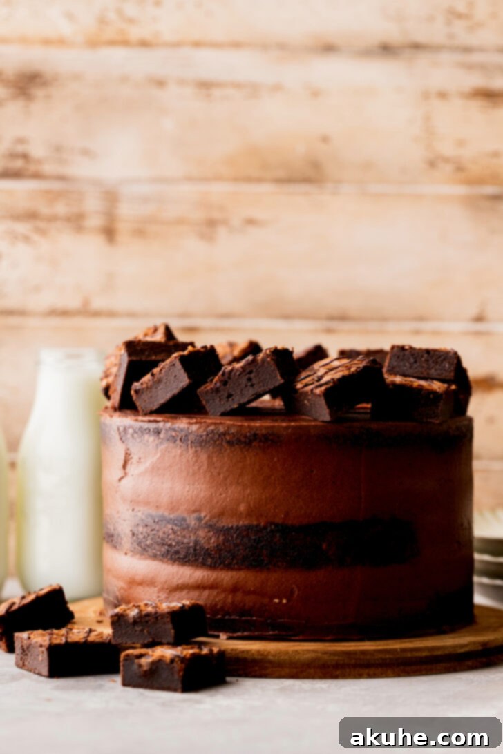 Fudgy Brownie Cake 11 A beautifully decorated brownie cake on a cake board, featuring a semi-naked frosting look and topped with brownie pieces