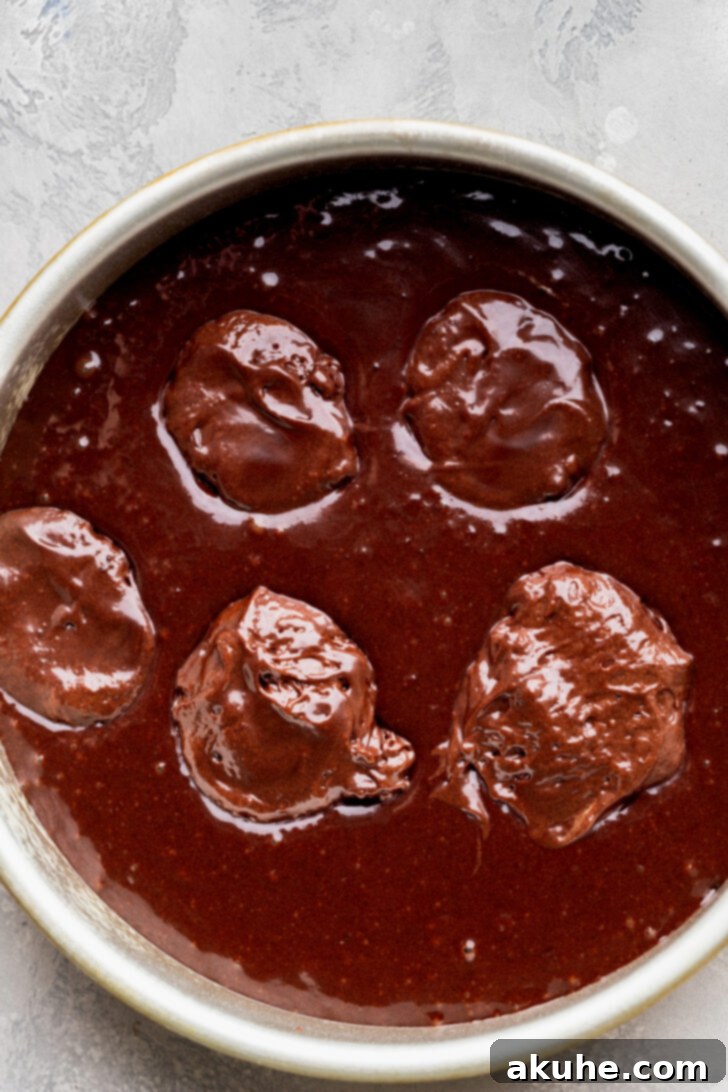 Fudgy Brownie Cake 6 Evenly spaced dollops of fudgy brownie batter spread over a layer of chocolate cake batter in a baking pan