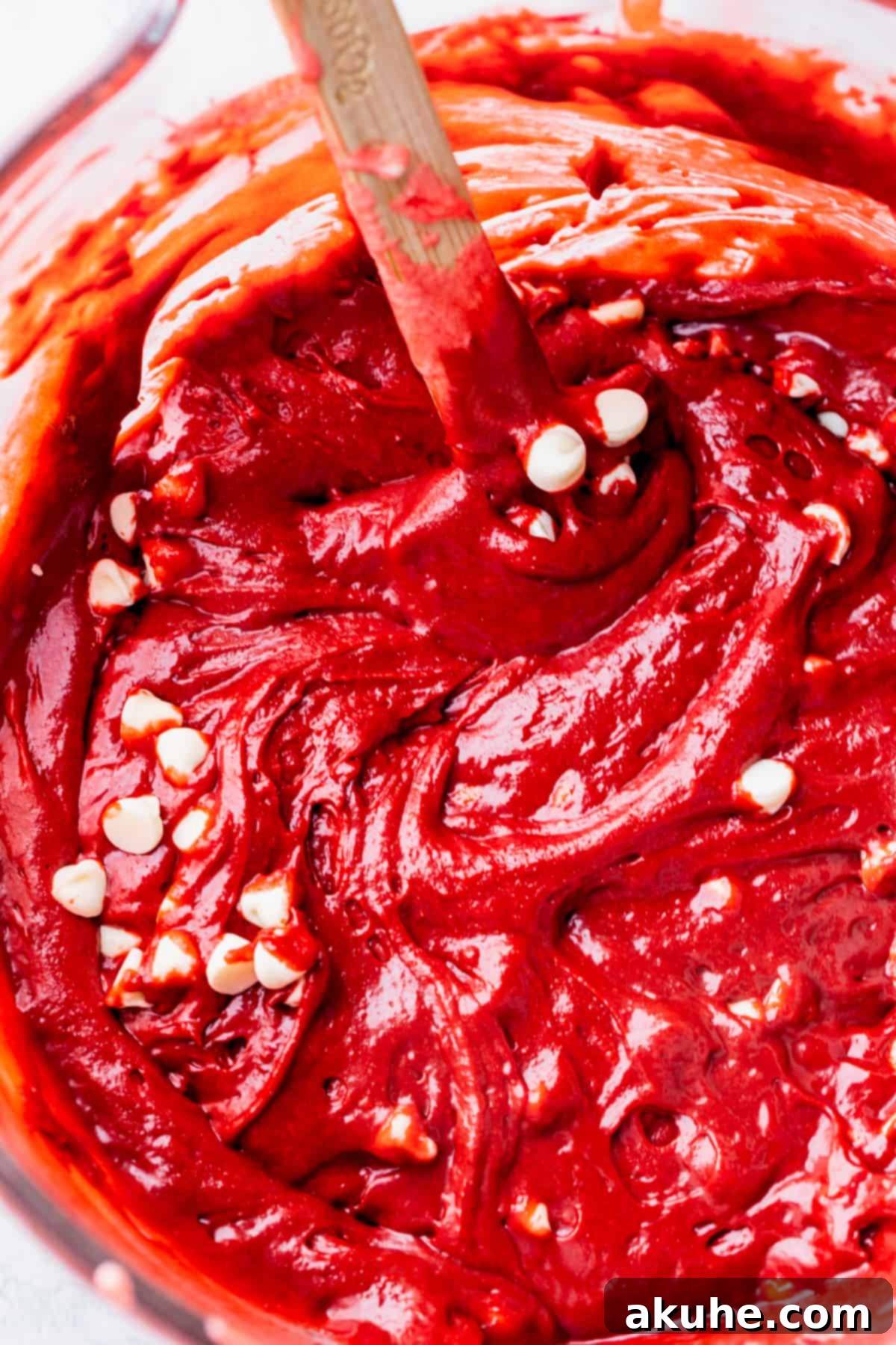 Brownie batter with white chocolate chips in a glass bowl.