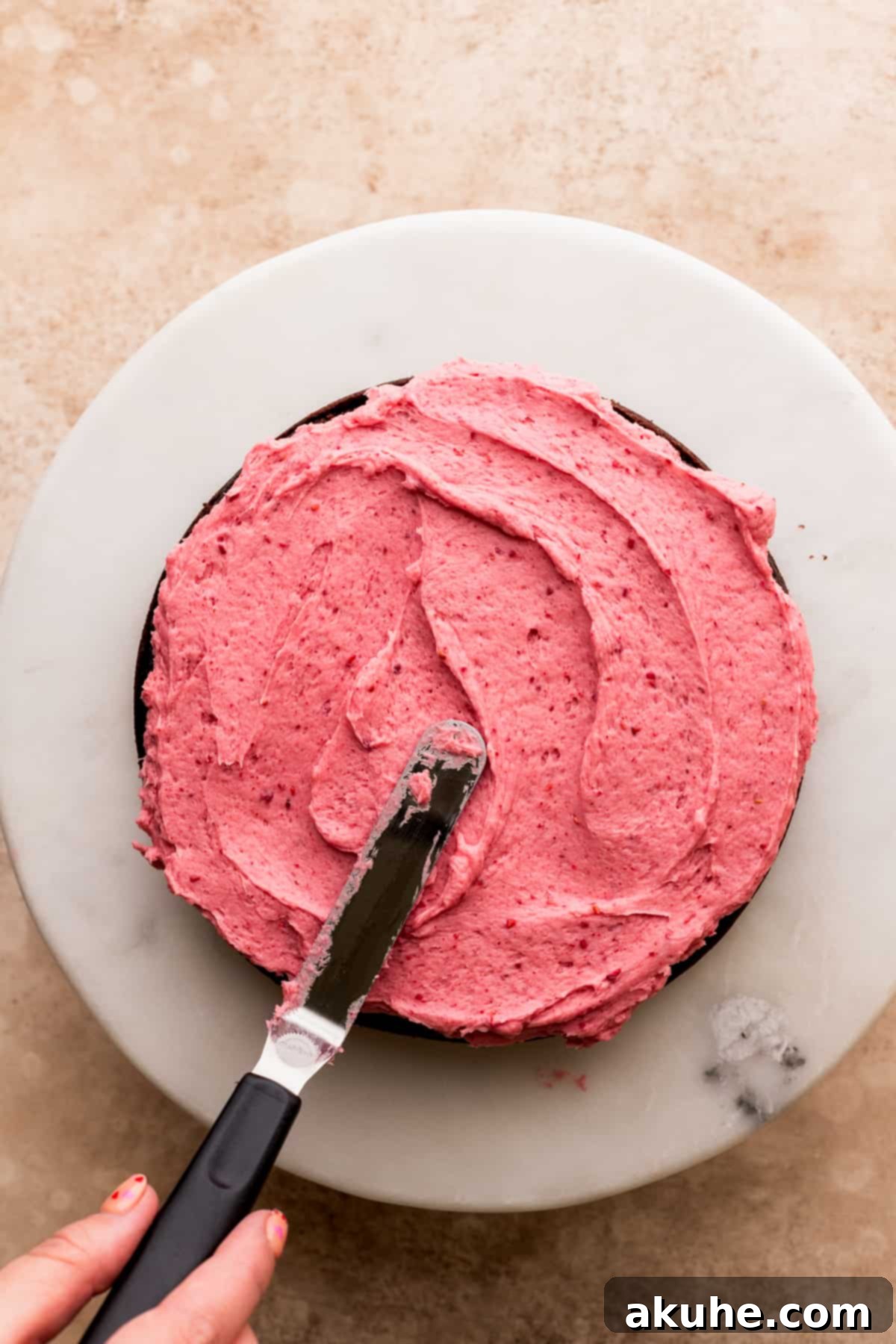 Decadent Chocolate Raspberry Delight 8 Spreading frosting on top of a cake layer.