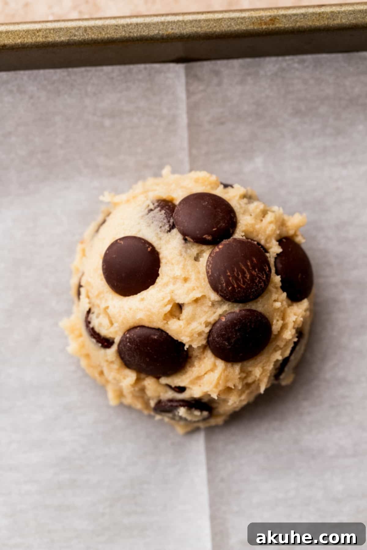 Irresistible Eggless Chocolate Chip Cookies 7 Individual cookie dough ball on a parchment-lined cookie sheet, ready for baking.