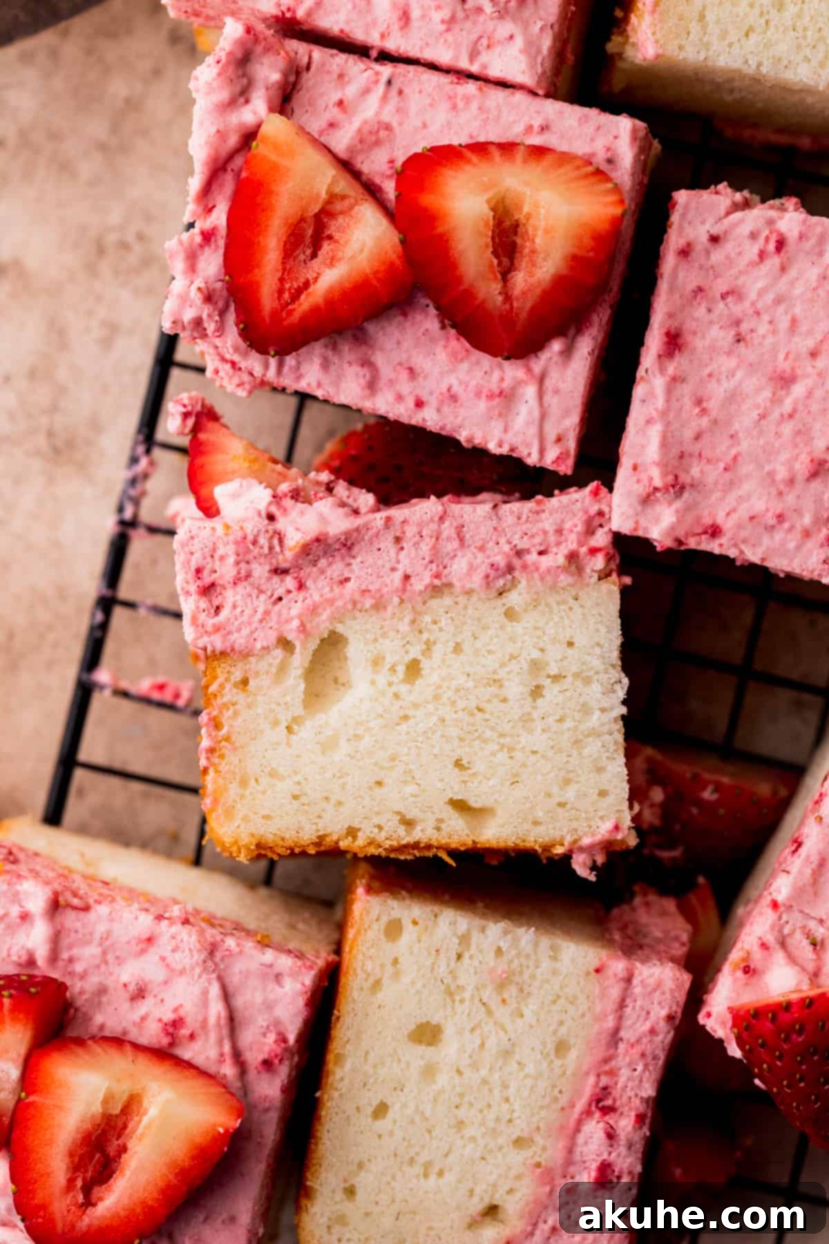 Several slices of freshly baked white cake cooling on a metal wire rack, ready for the strawberry mousse topping.