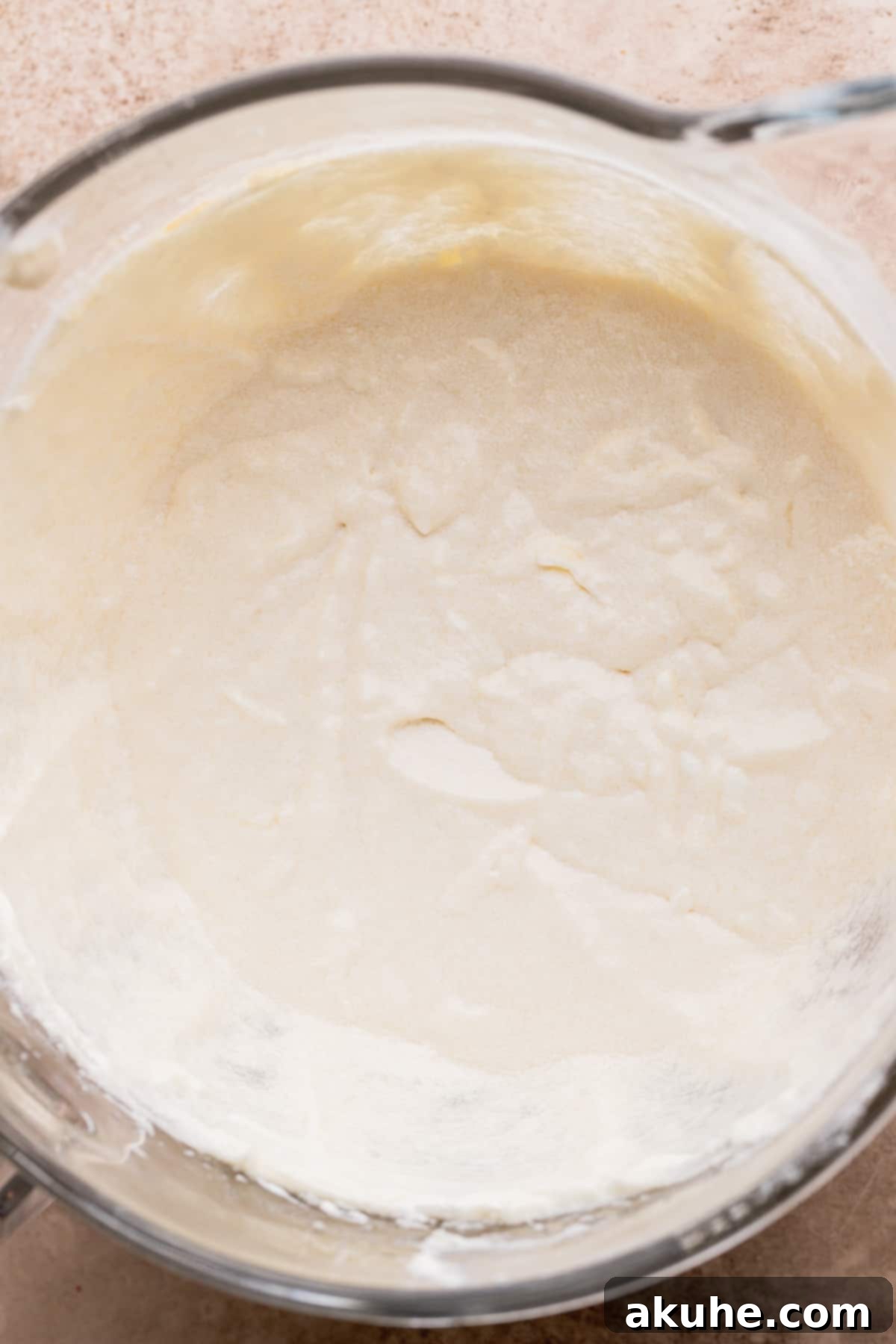 A glass bowl containing the wet ingredients mixture, including butter, sugar, oil, egg whites, vanilla, and sour cream, blended to a smooth consistency.