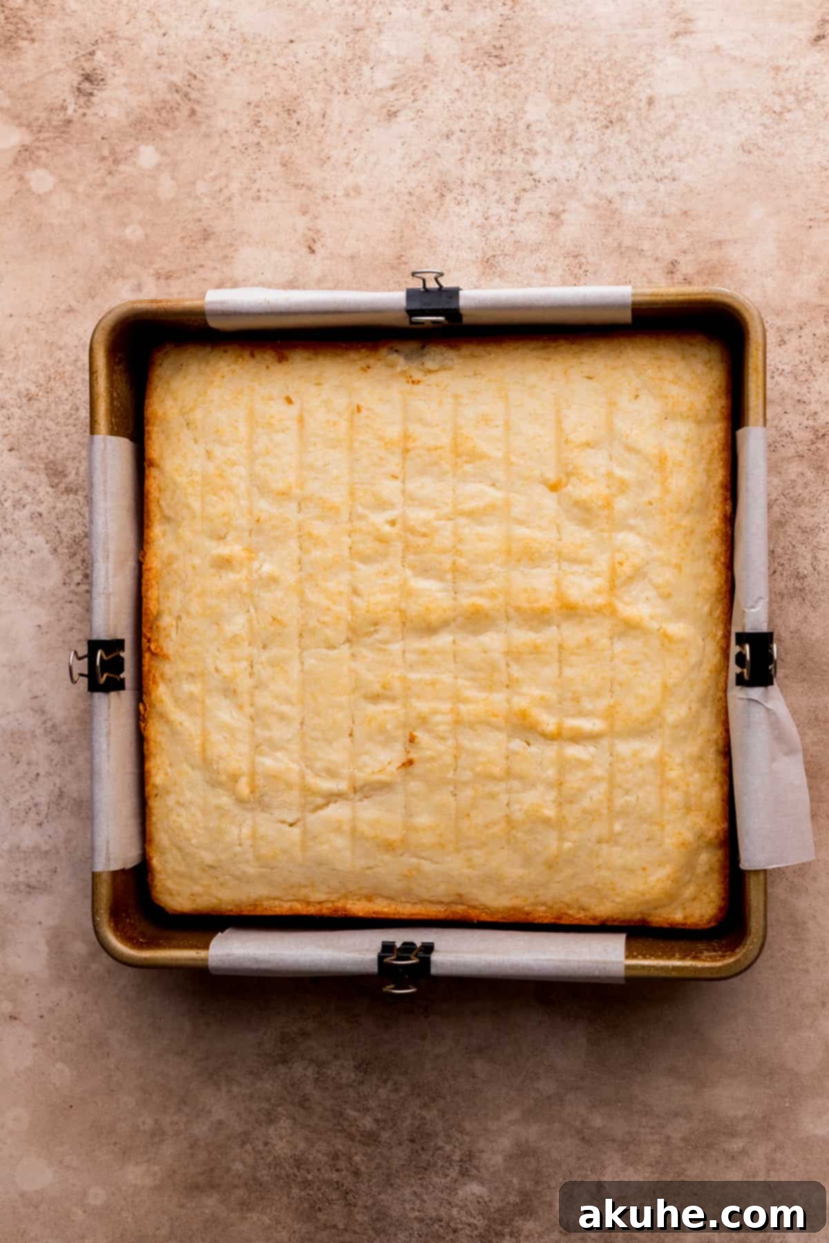The baked white cake layer perfectly placed in a prepared square pan, awaiting its strawberry mousse topping.