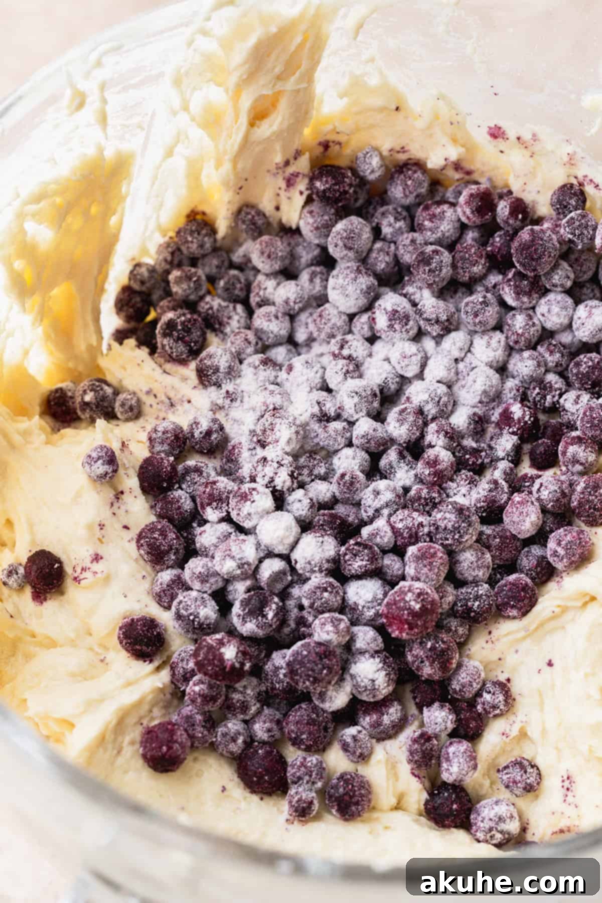 Bursting Berry Bliss 6 Fresh blueberries gently resting on top of a creamy cake batter in a clear glass bowl, ready to be folded in.