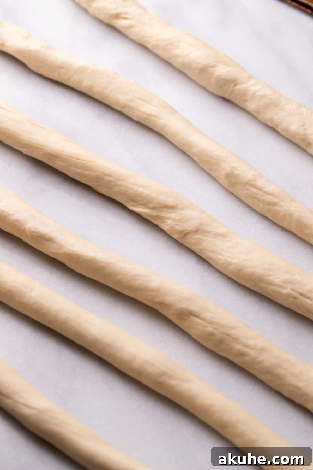 Perfectly Poppable Pretzels 6 Six long ropes of pretzel dough on a cutting board.