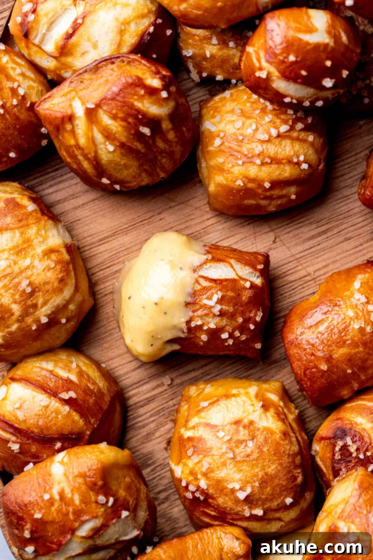 Perfectly Poppable Pretzels 10 Close-up of a soft pretzel bite being dipped into creamy nacho cheese sauce.