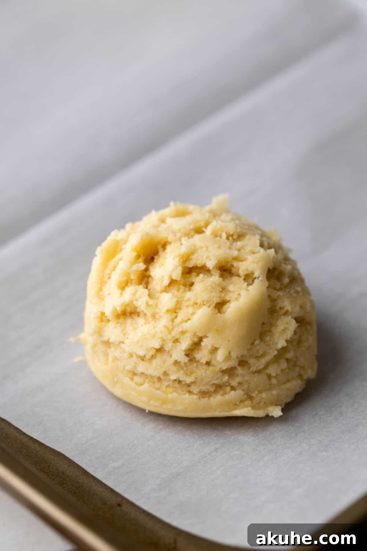 Zesty Lemon Bites 6 Individual lemon cookie dough ball on parchment paper, ready to bake.