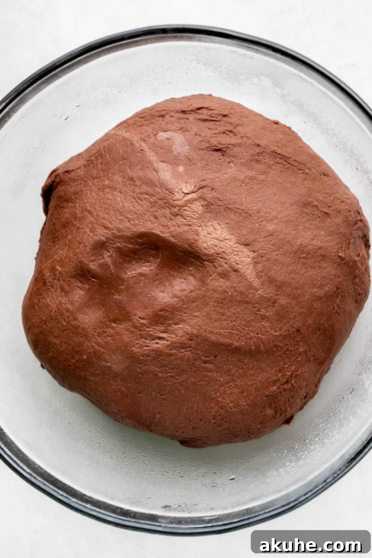 Decadent Chocolate Rolls 5 Raised chocolate dough in a glass bowl after resting, significantly increased in volume.