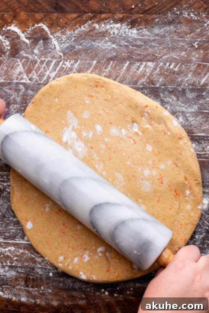 Carrot Cake Cinnamon Swirls 5 A baker carefully rolling out the carrot cake dough on a floured surface.
