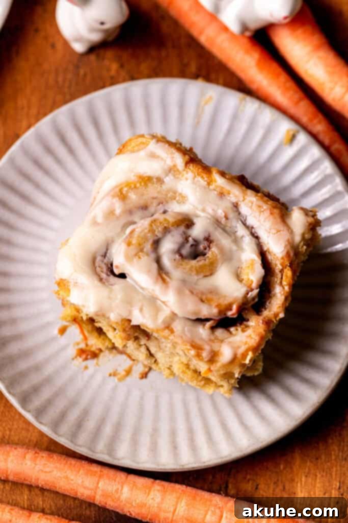 Carrot Cake Cinnamon Swirls 10 Top view of one carrot cake cinnamon roll on a plate, ready to be eaten.
