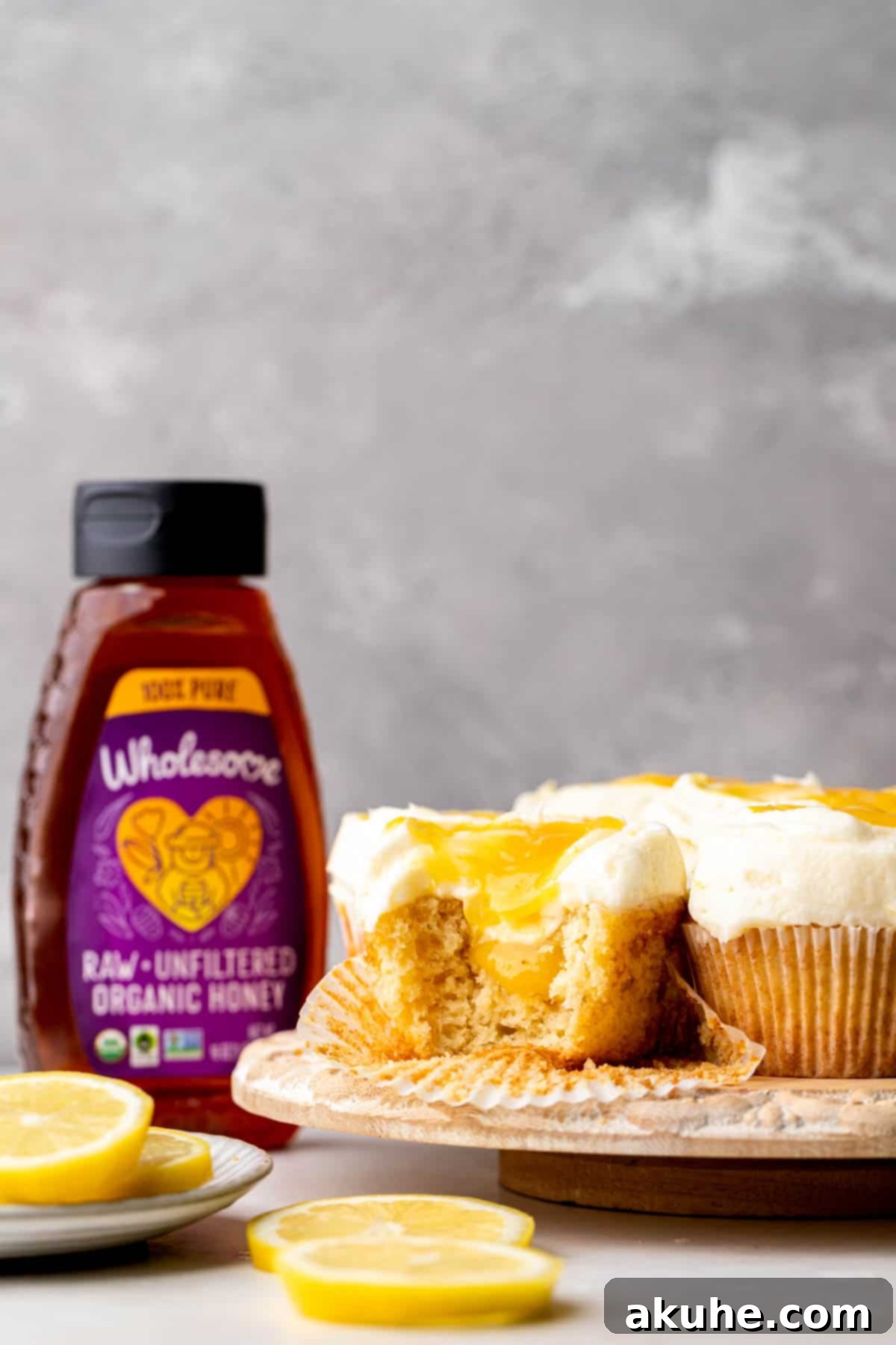 A single lemon bar cupcake with a bite taken out, resting on a wooden platter, showcasing its moist interior.