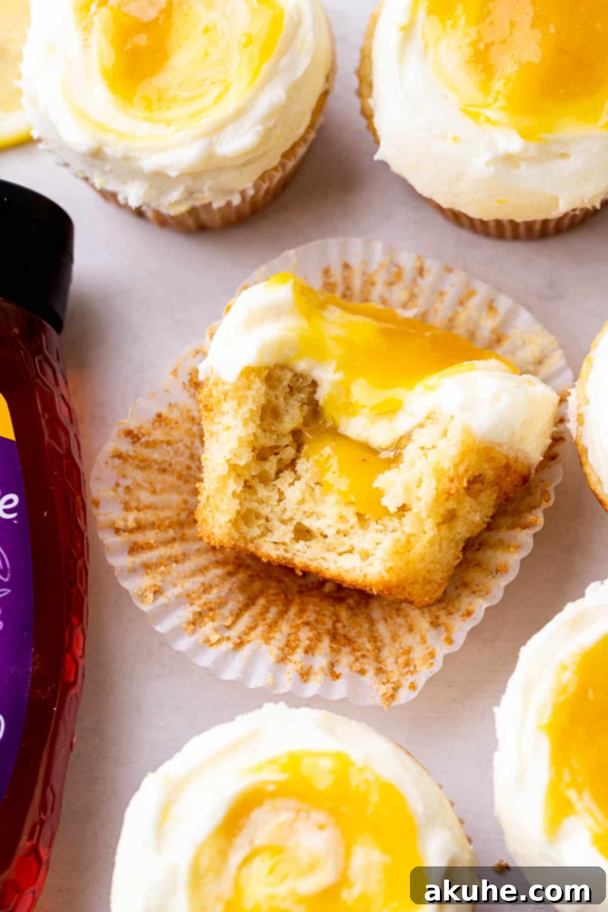 Two lemon bar cupcakes side by side, one with a bite removed, showcasing their tempting appearance.