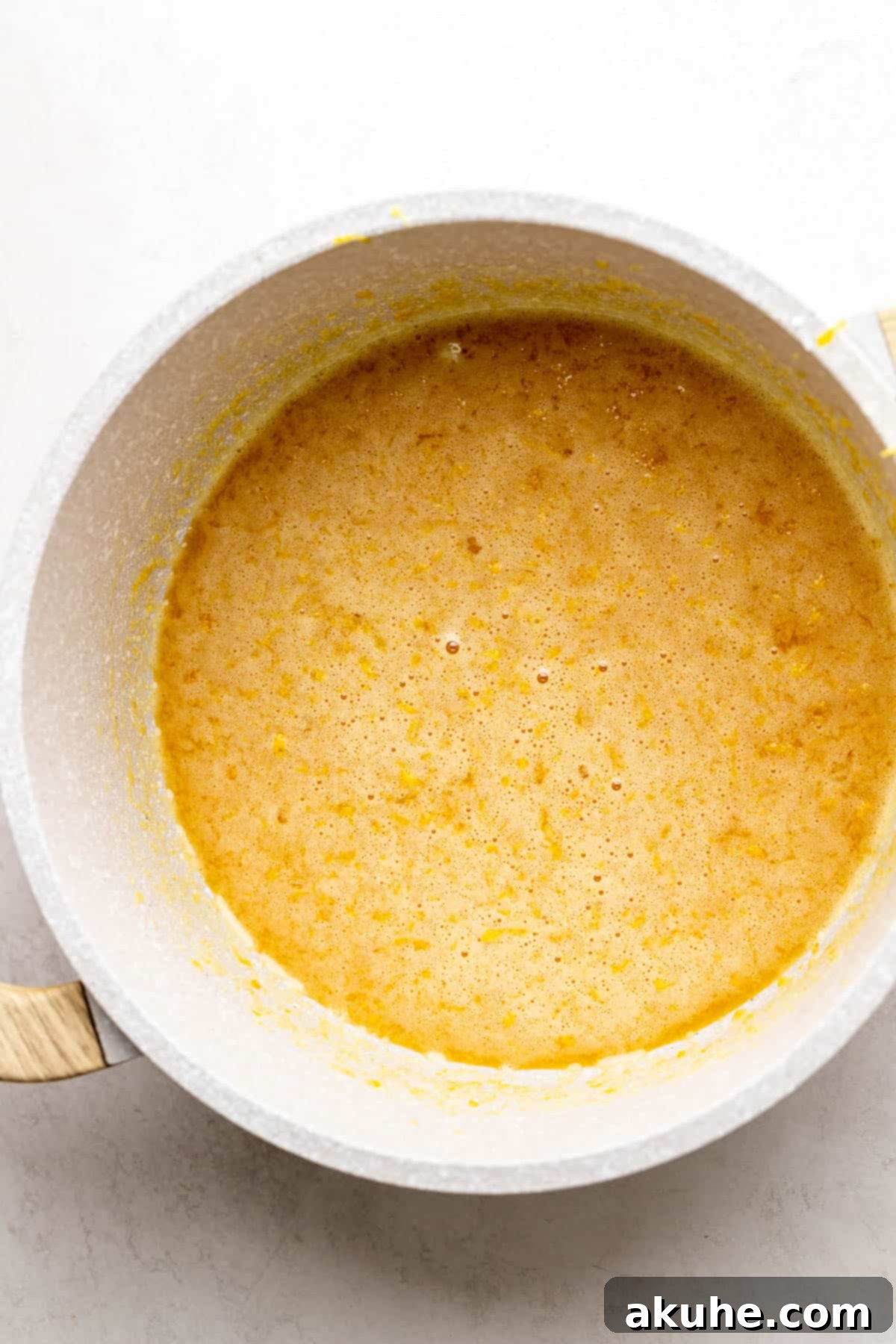 Wet ingredients for lemon bar filling being whisked together in a saucepan.
