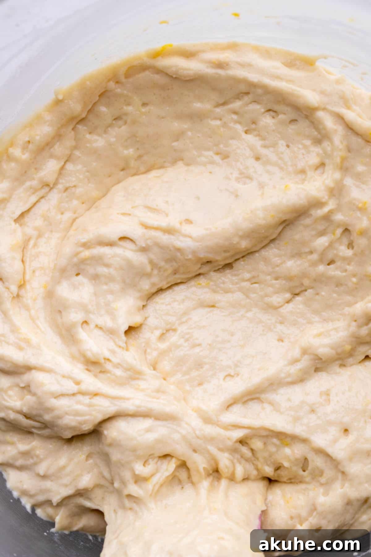 Smooth lemon cupcake batter resting in a clear glass bowl, showcasing its creamy texture.