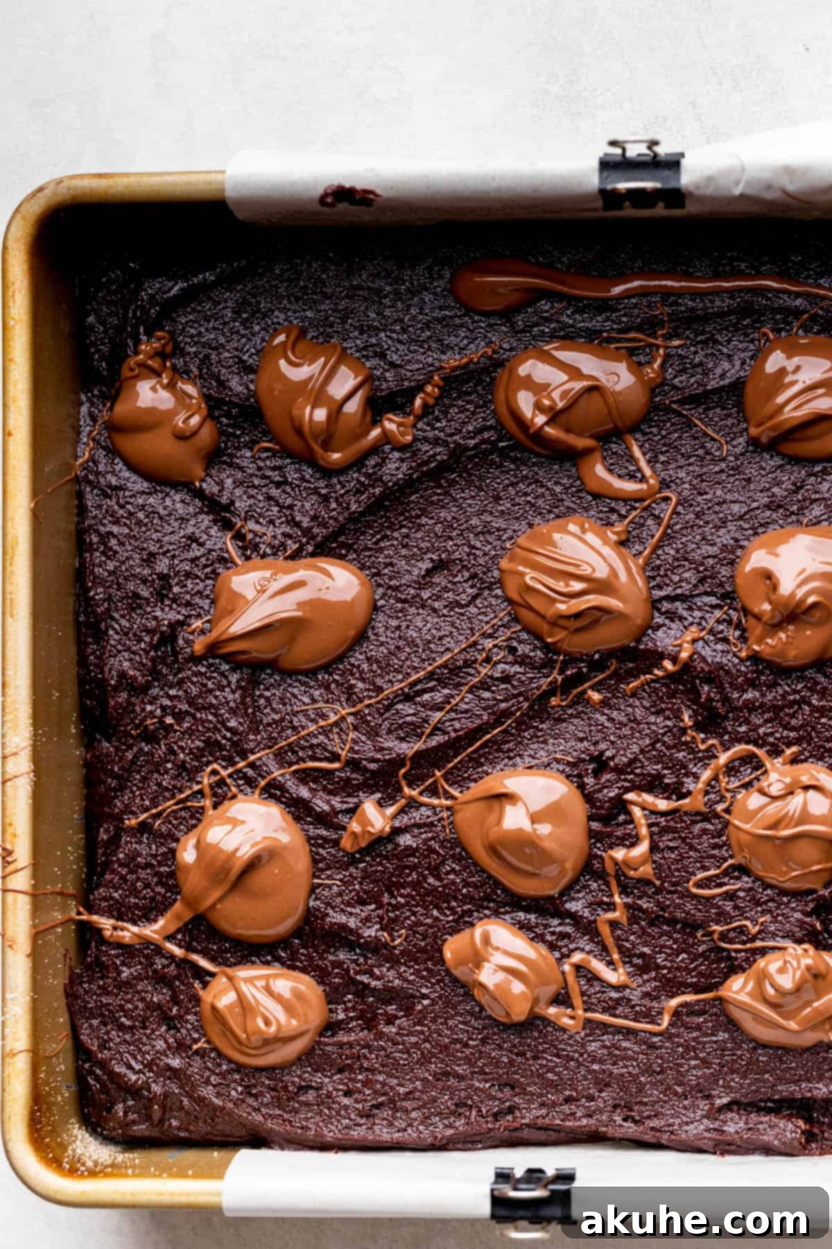 Decadent Nutella Brownies 7 Dollops of Nutella spread across the brownie batter in a pan, before swirling.