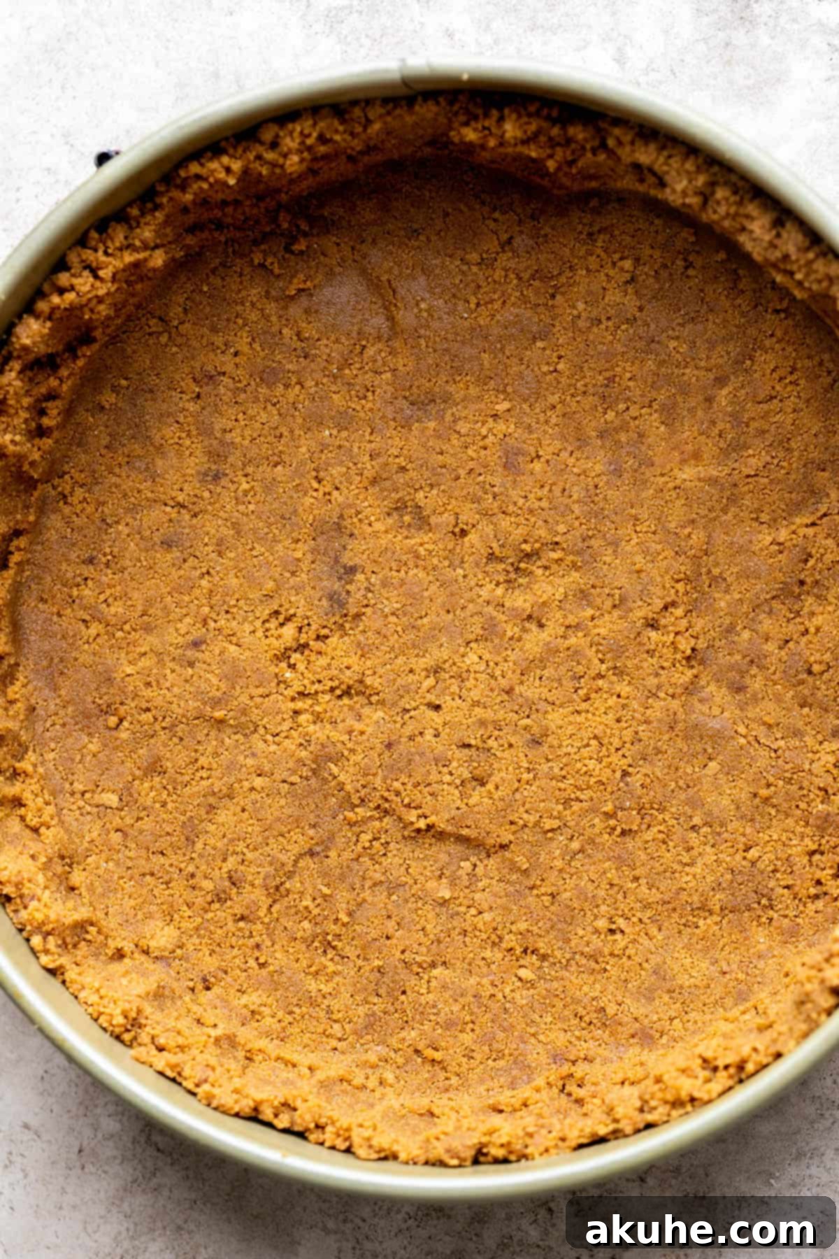 Decadent Gluten-Free Cheesecake 5 Graham cracker crust meticulously formed in a springform pan, showing an even base and sides.