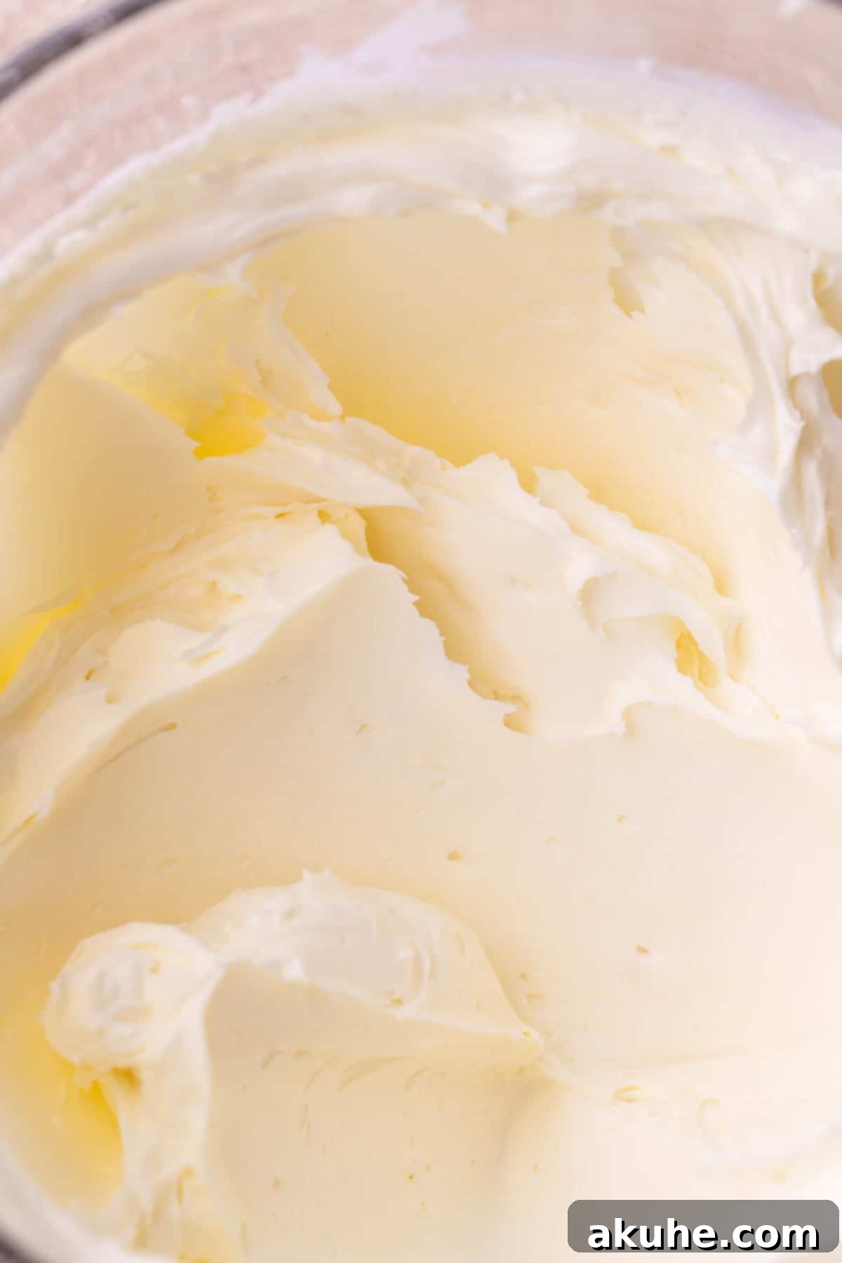 Decadent Gluten-Free Cheesecake 6 Whipped cream cheese and sugar in a glass bowl, showing a smooth and airy consistency.