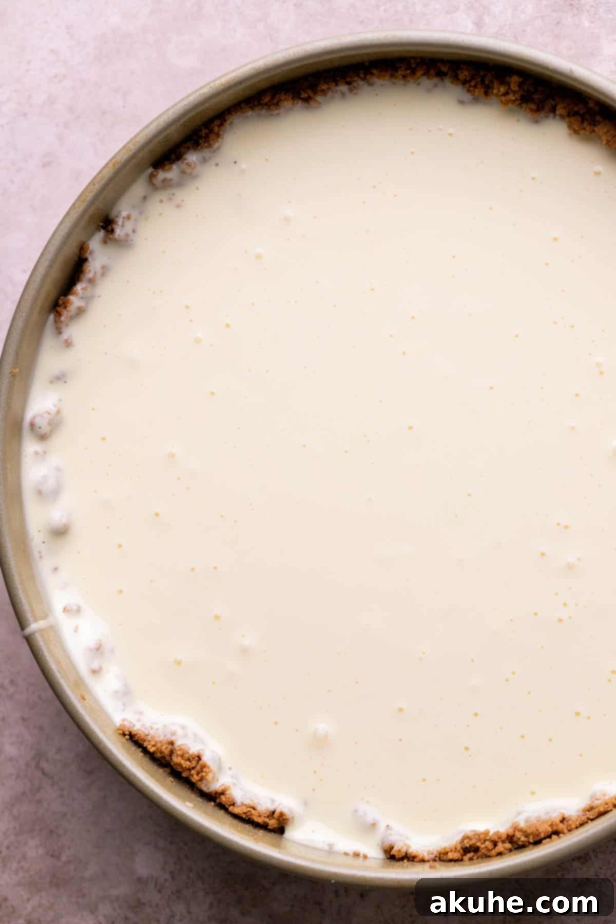 Decadent Gluten-Free Cheesecake 8 Smooth cheesecake batter poured onto the crust in a springform pan, ready for the water bath.