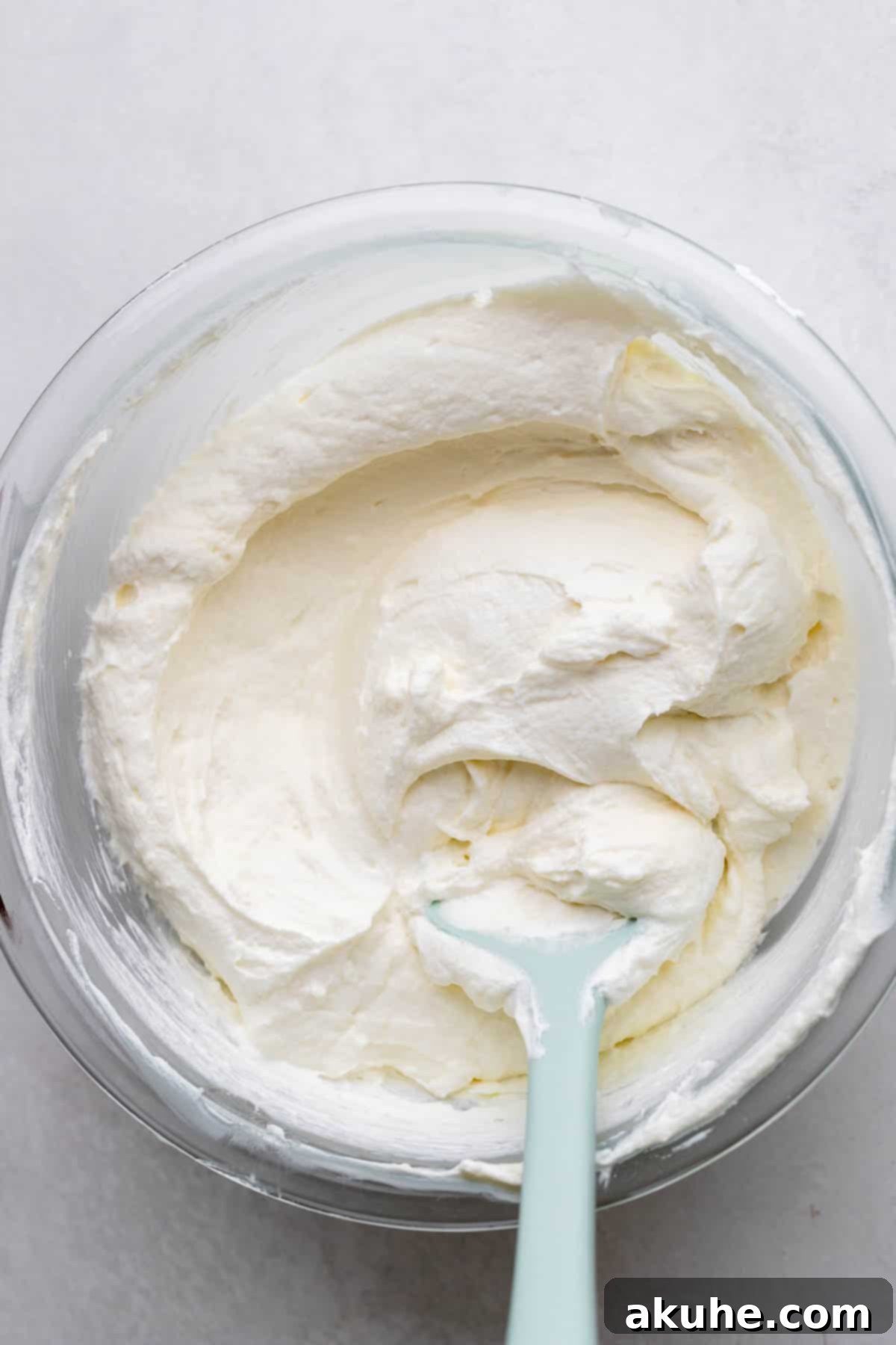 Smooth whipped cream cheese mixture in a clear glass bowl.