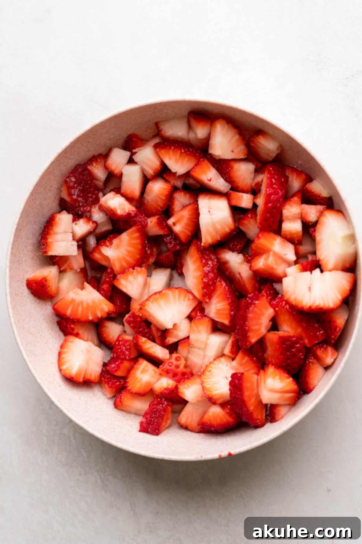 Bowl of diced strawberries mixed with sugar, macerating.