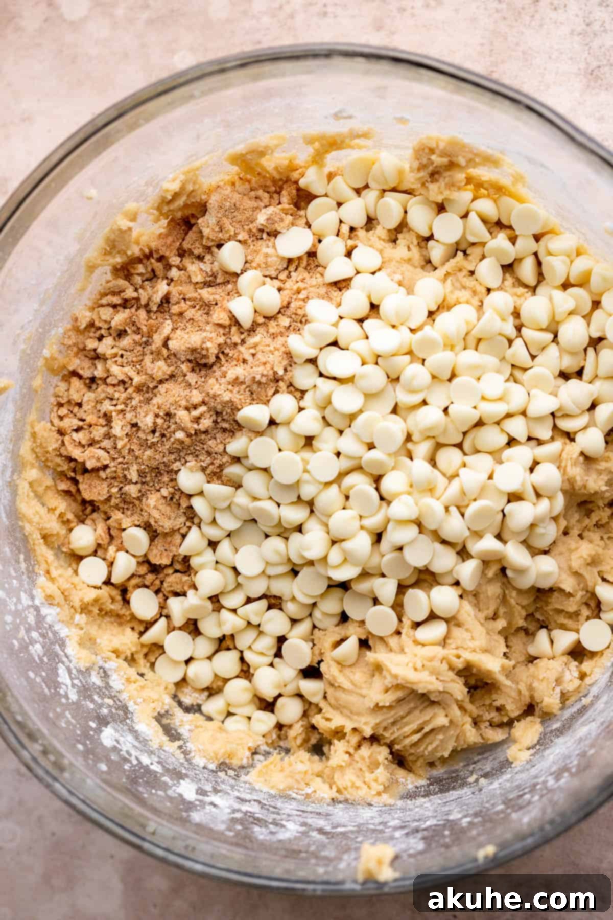 Crunchy Cinnamon Toast Cereal Cookies 5 Cinnamon Toast Crunch crumbs and white chocolate chips resting on top of cookie dough in a bowl.