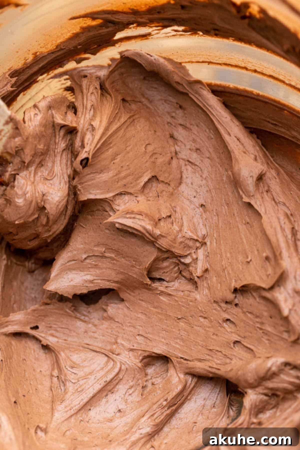 Rich chocolate frosting in a glass bowl, ready for spreading.