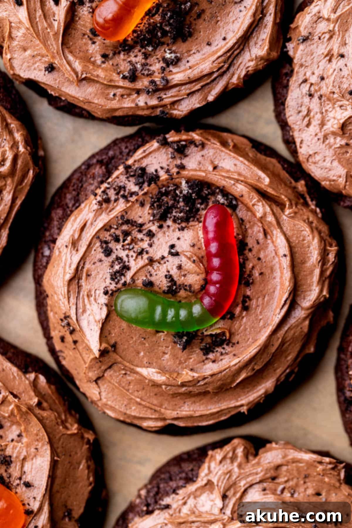 Close up of a decorated dirt cake cookie, showing the detail of the frosting, Oreo crumbs, and gummy worm.