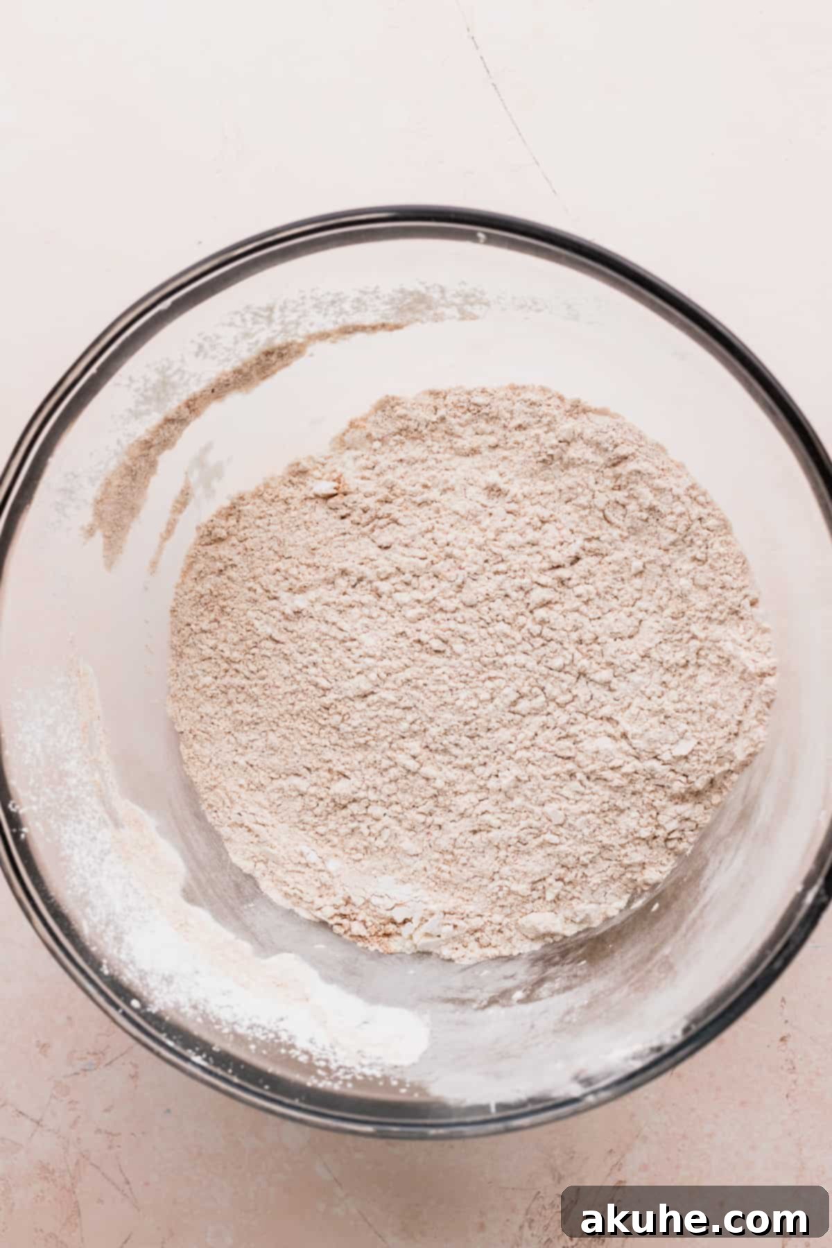Dry ingredients in a clear glass mixing bowl, ready to be combined with wet ingredients.