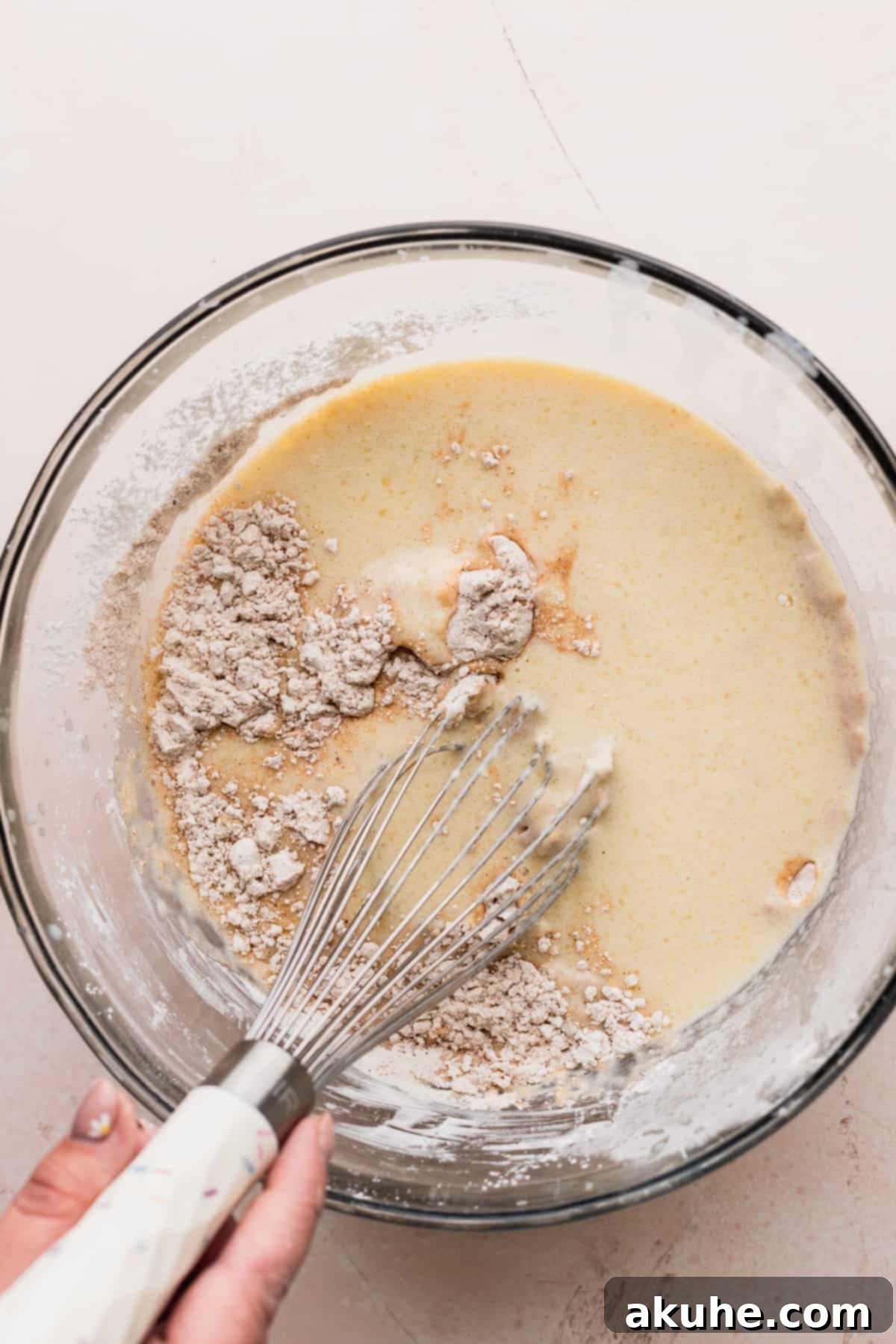 Wet ingredients, including mashed bananas and liquids, in a separate bowl, showcasing their creamy texture.