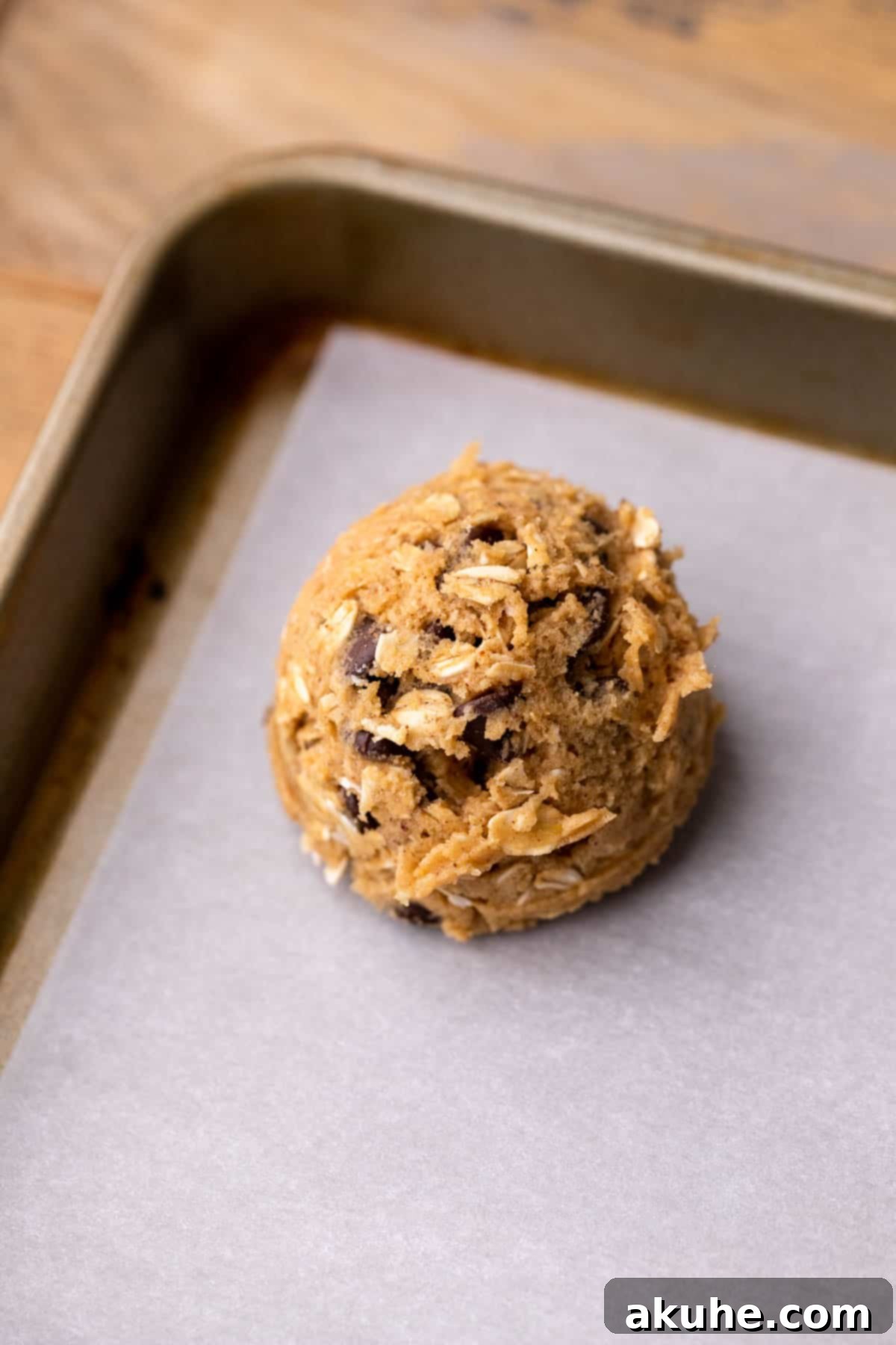 A perfectly portioned cookie dough ball on a parchment-lined cookie sheet.