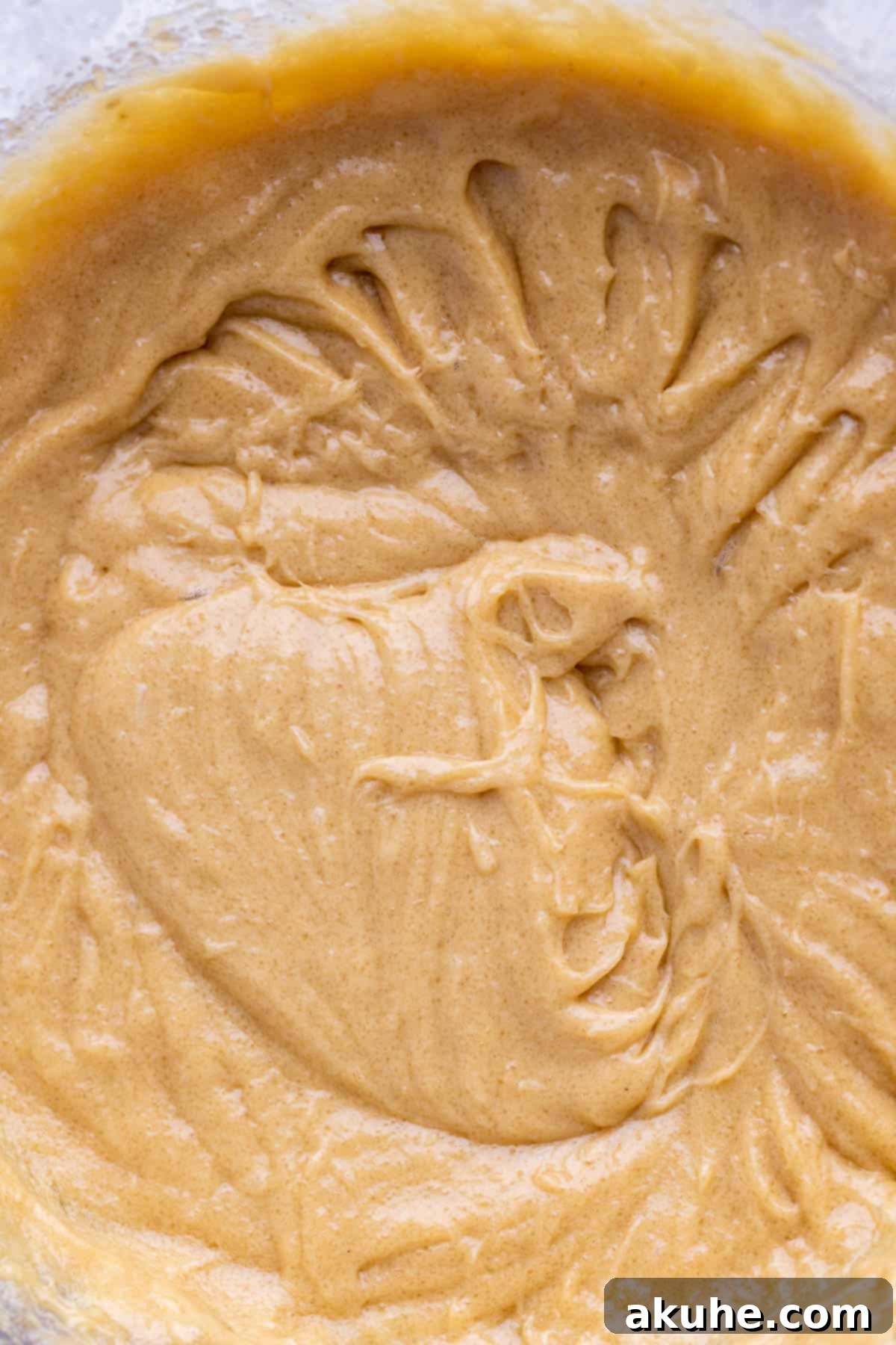 Bowl with wet ingredients mixed, a light brown, creamy mixture.