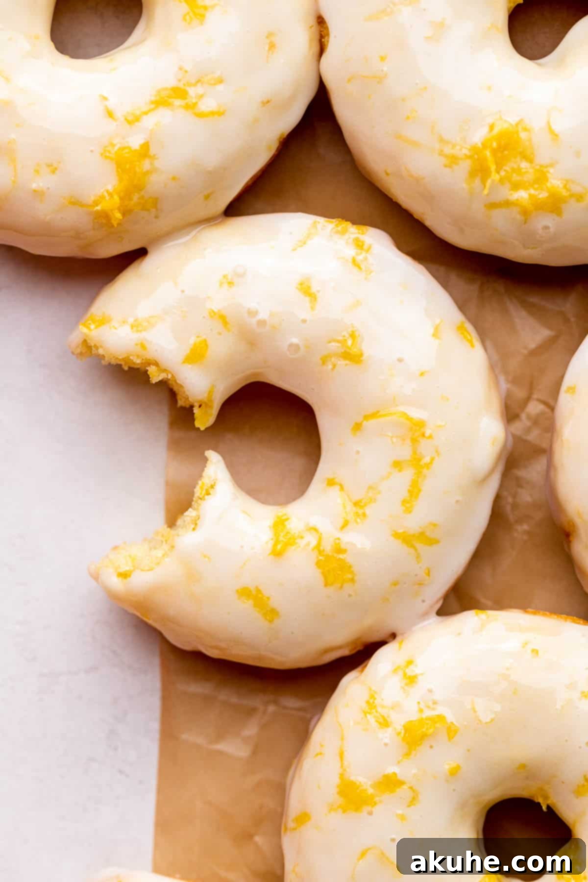 Zesty Lemon Donuts 2 A perfectly baked lemon donut with a bite taken out, showing its fluffy interior.