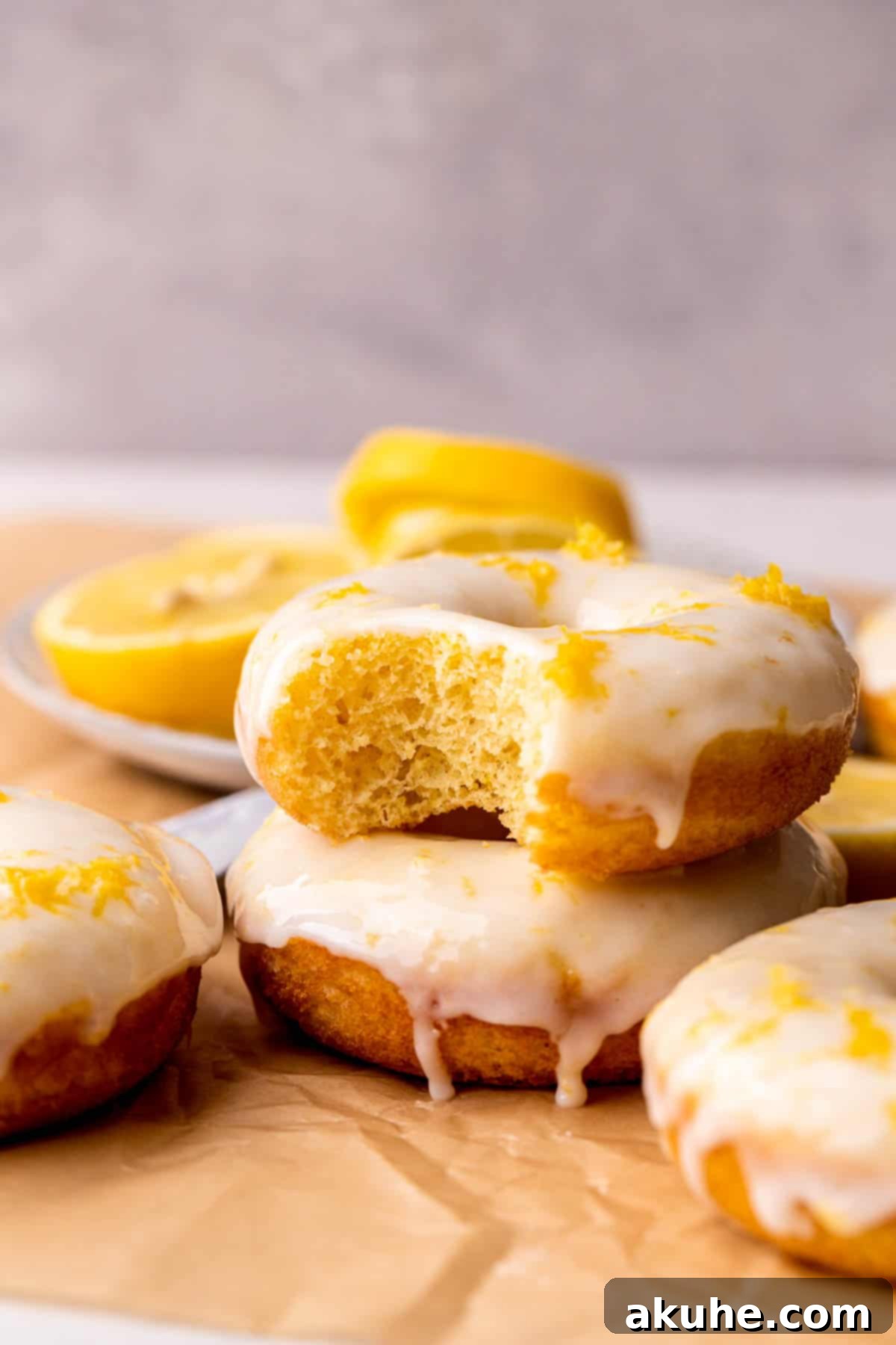 Zesty Lemon Donuts 3 A few lemon donuts, one with a bite taken out, displaying the light, airy texture.