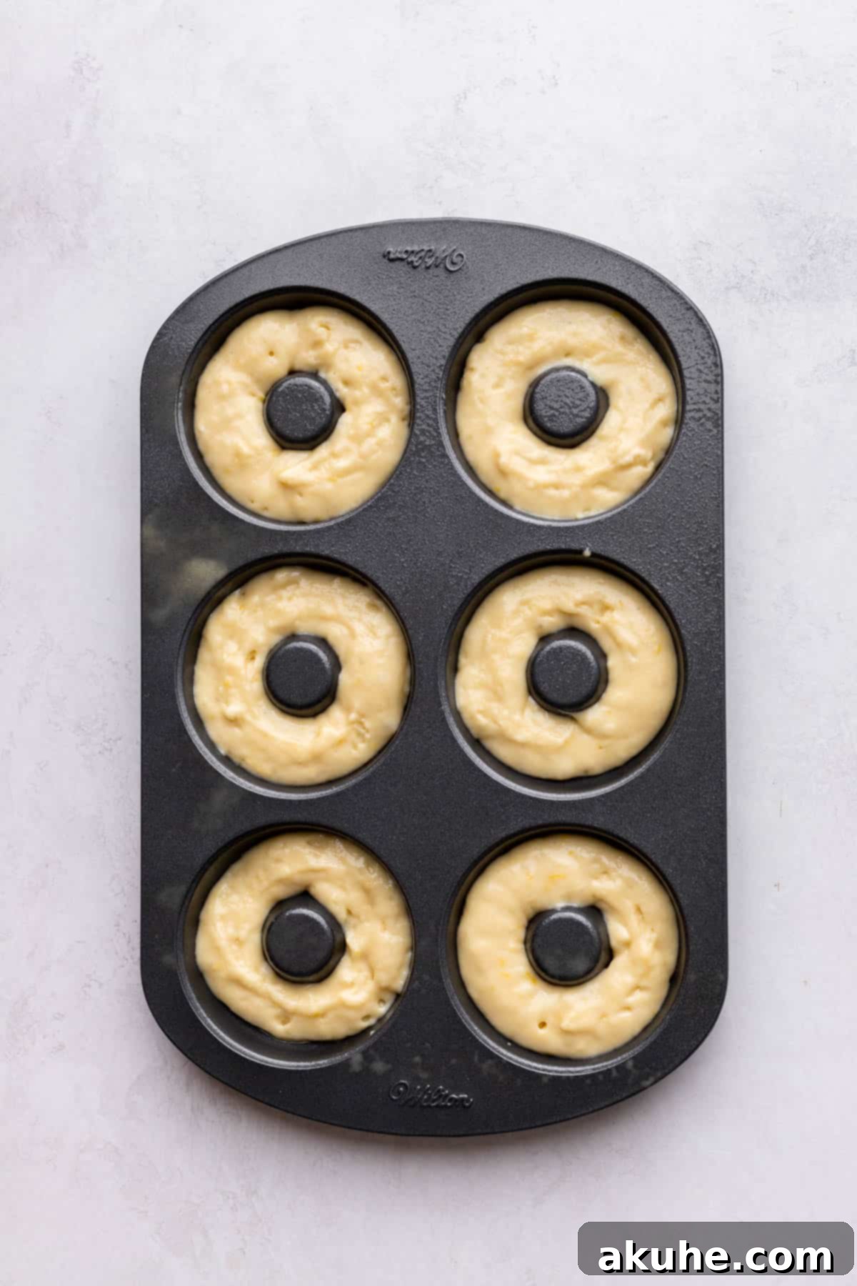 Zesty Lemon Donuts 6 Donut batter neatly piped into a donut pan, ready for baking.