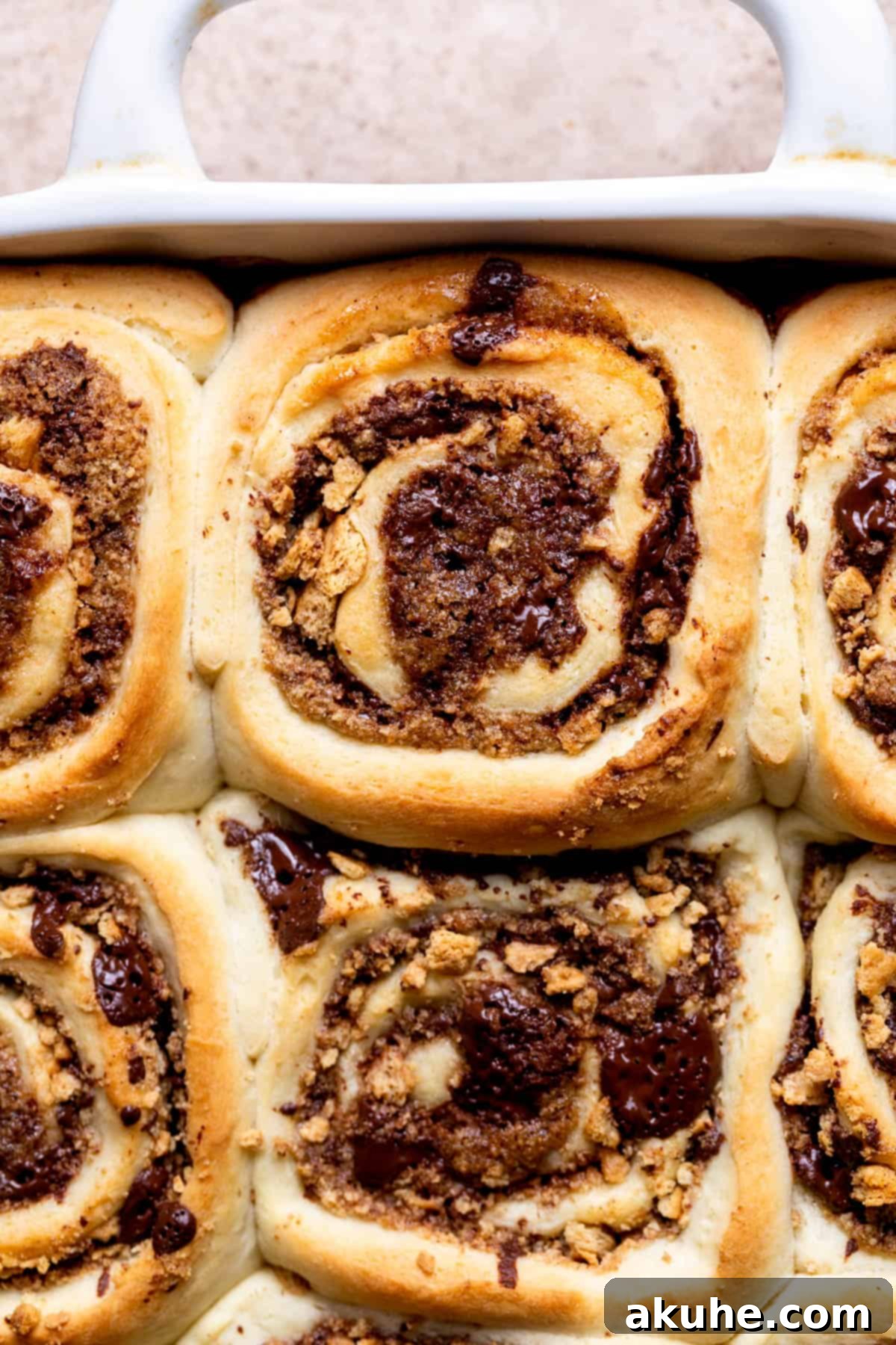 Gooey S'mores Cinnamon Buns 8 Freshly baked cinnamon rolls in a pan, golden brown and ready for topping.