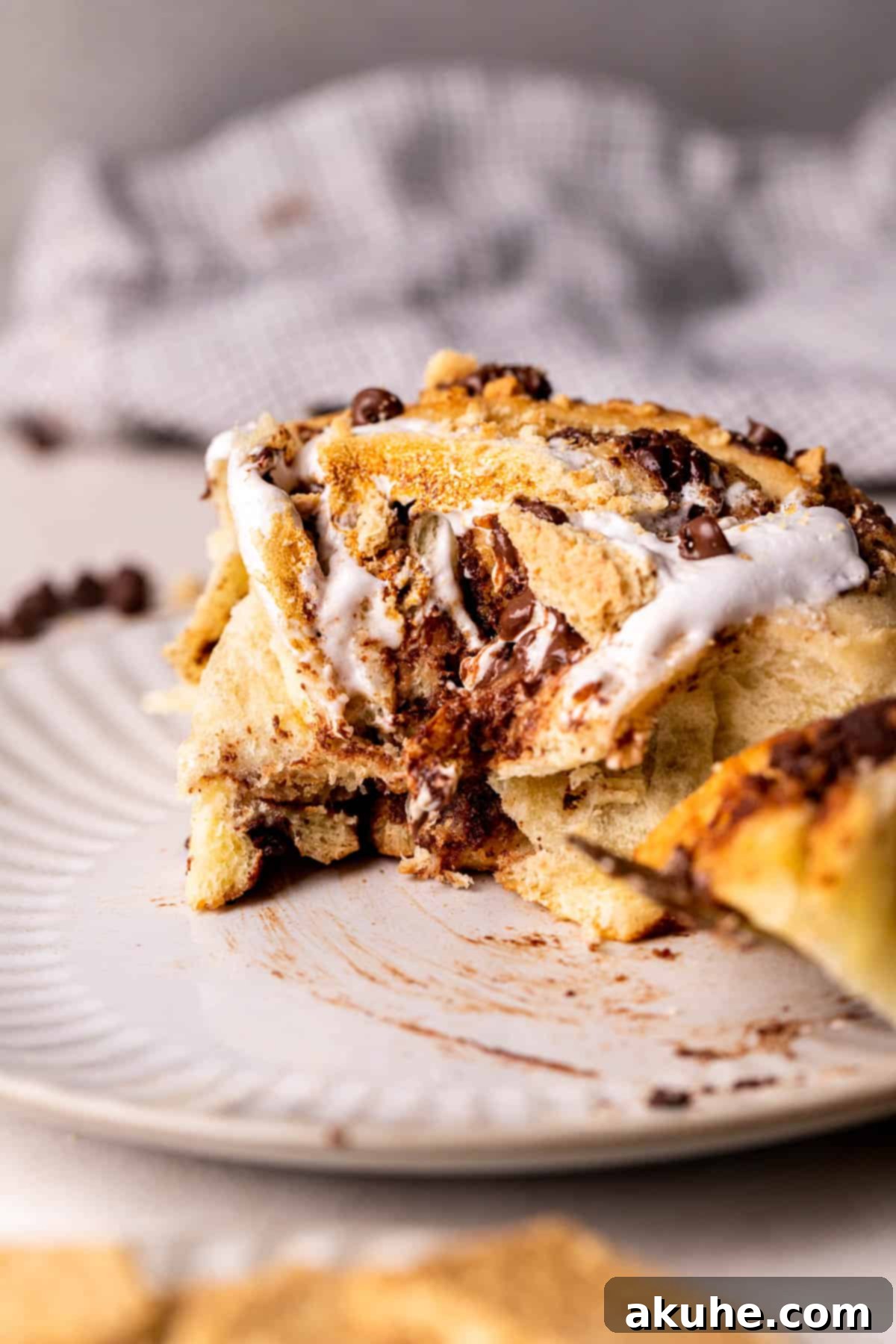 Gooey S'mores Cinnamon Buns 10 A S'mores Cinnamon Roll with a bite taken out, revealing its rich chocolate and graham cracker filling.