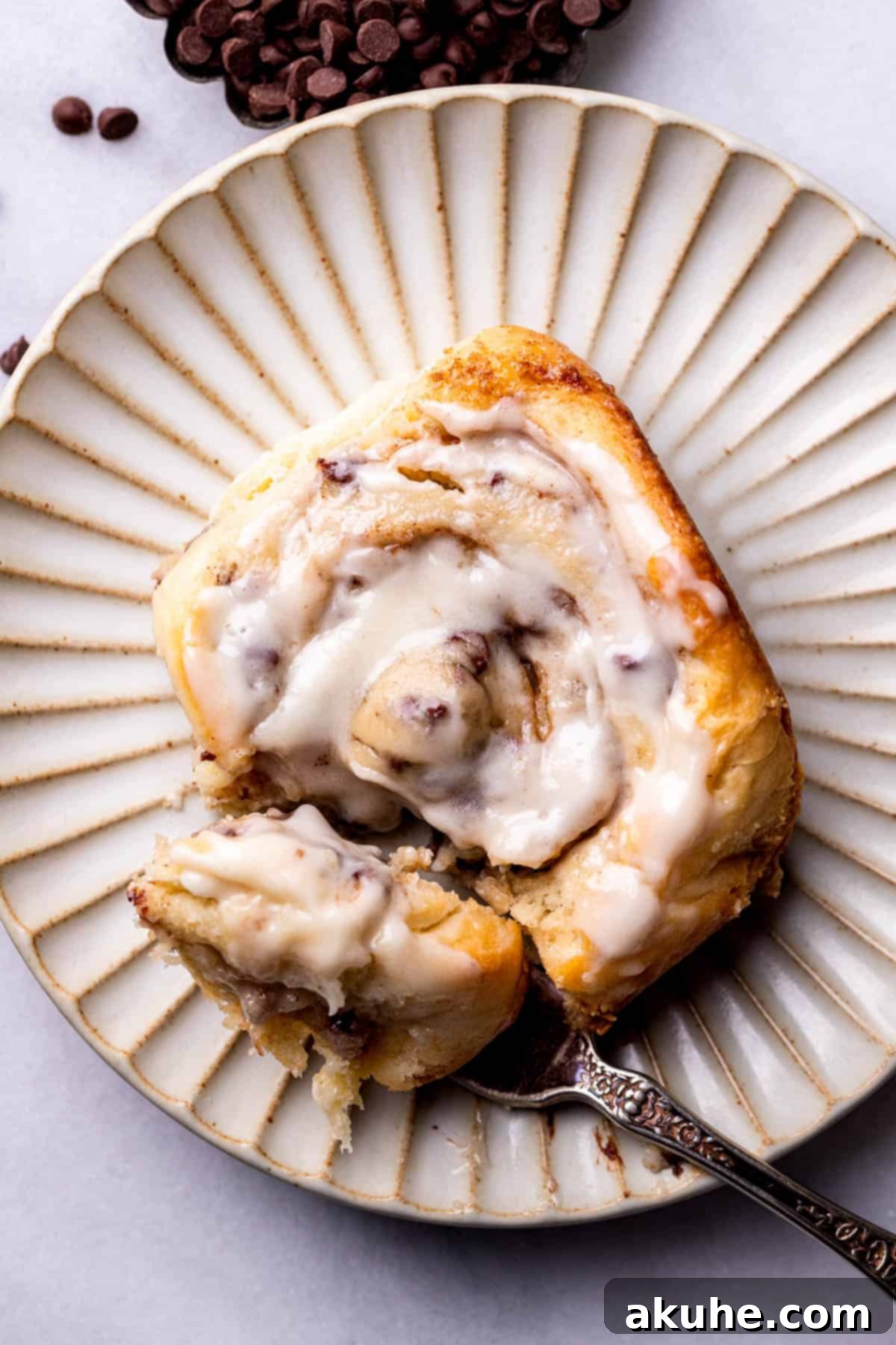 Cookie Dough Swirled Cinnamon Buns 11 A single, perfectly iced cookie dough cinnamon roll on a white plate, ready to be enjoyed.