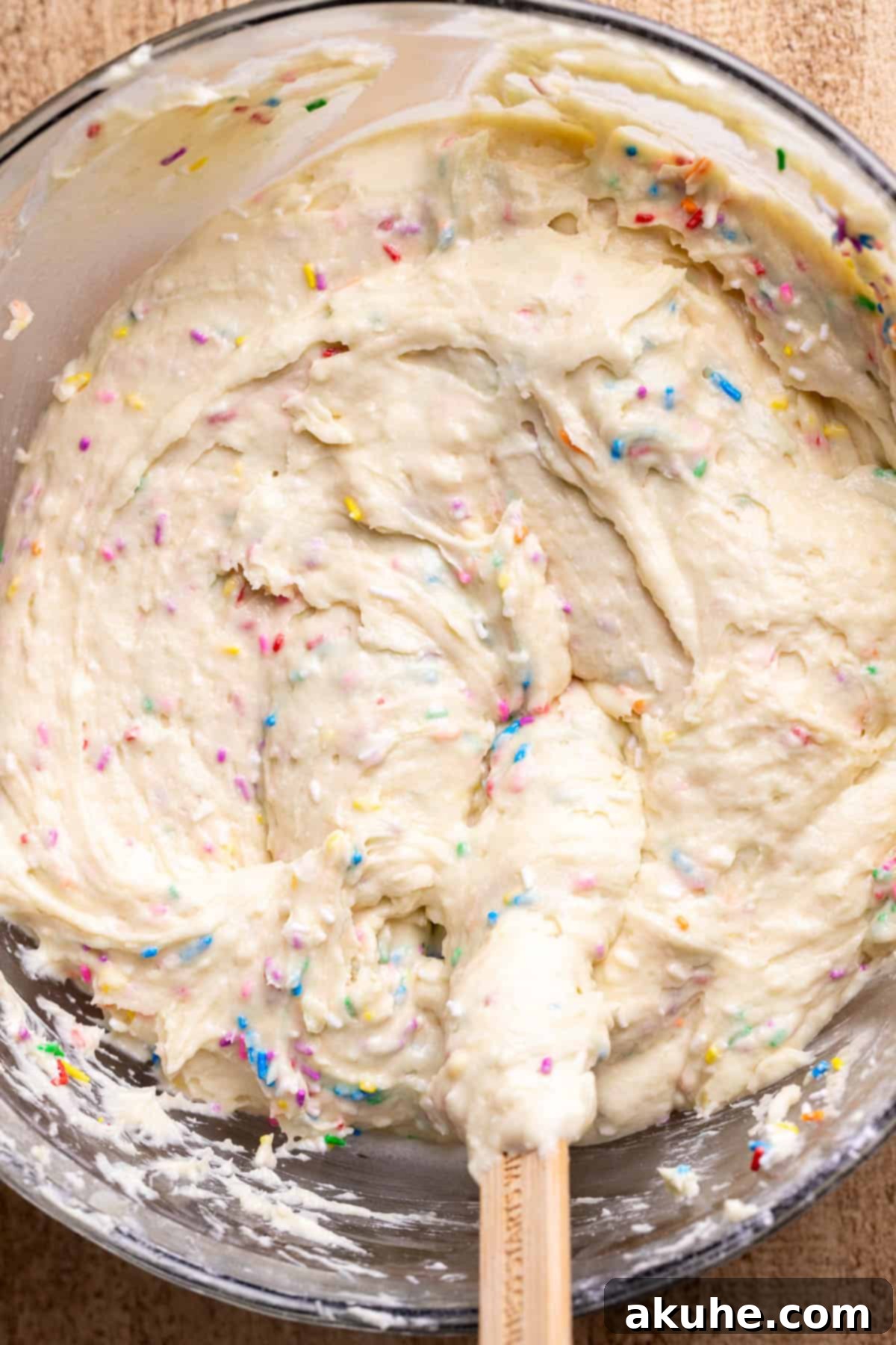 Festive Sprinkled Cake 5 Glass bowl filled with colorful funfetti cake batter, ready for baking.
